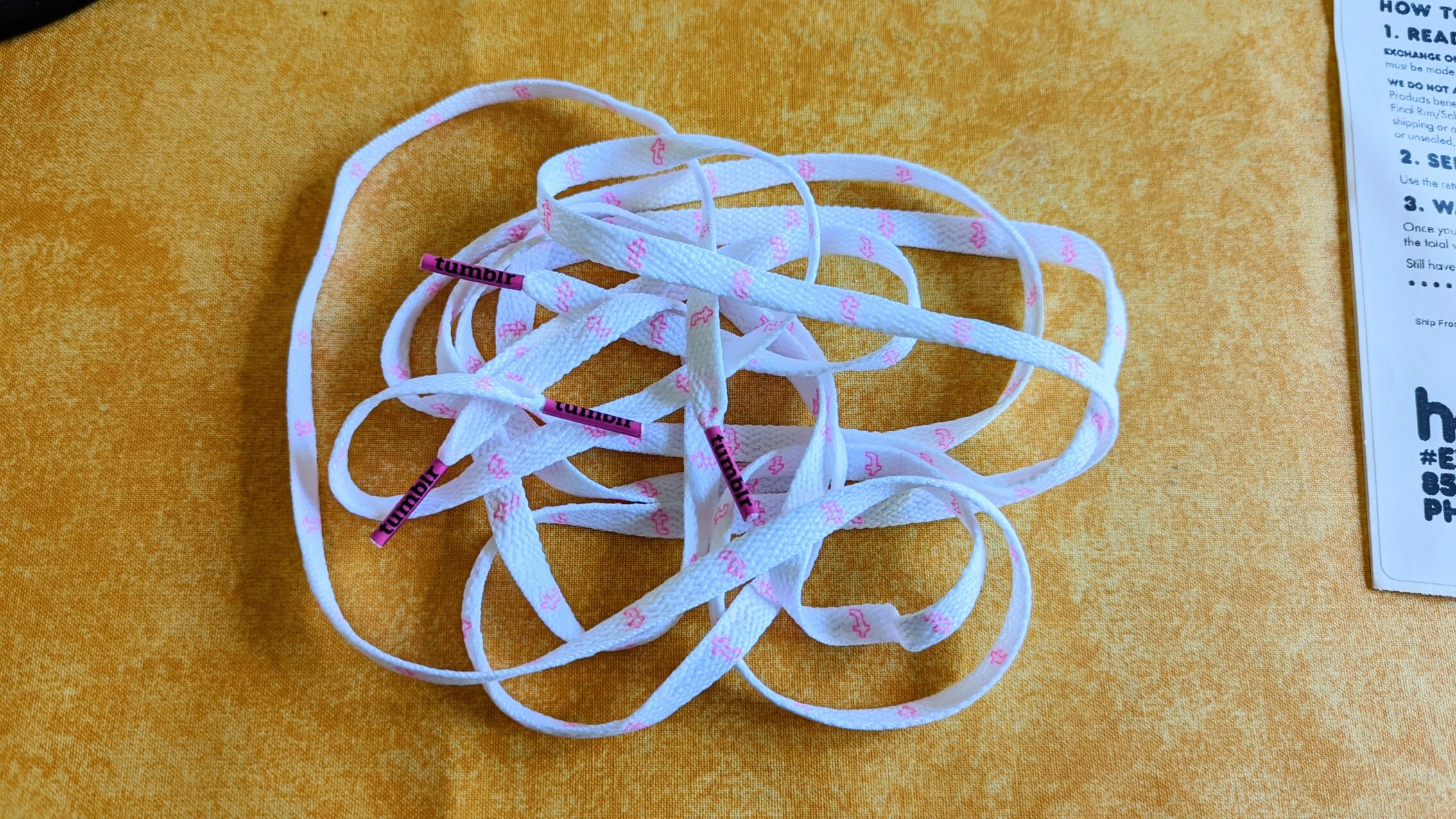 White shoelaces with the Tumblr logo in pink.