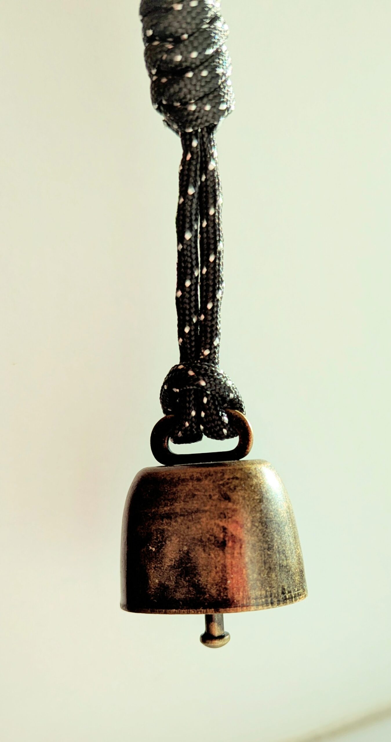 Close-up of a metal bell on a string that you can fasten on your backpack.