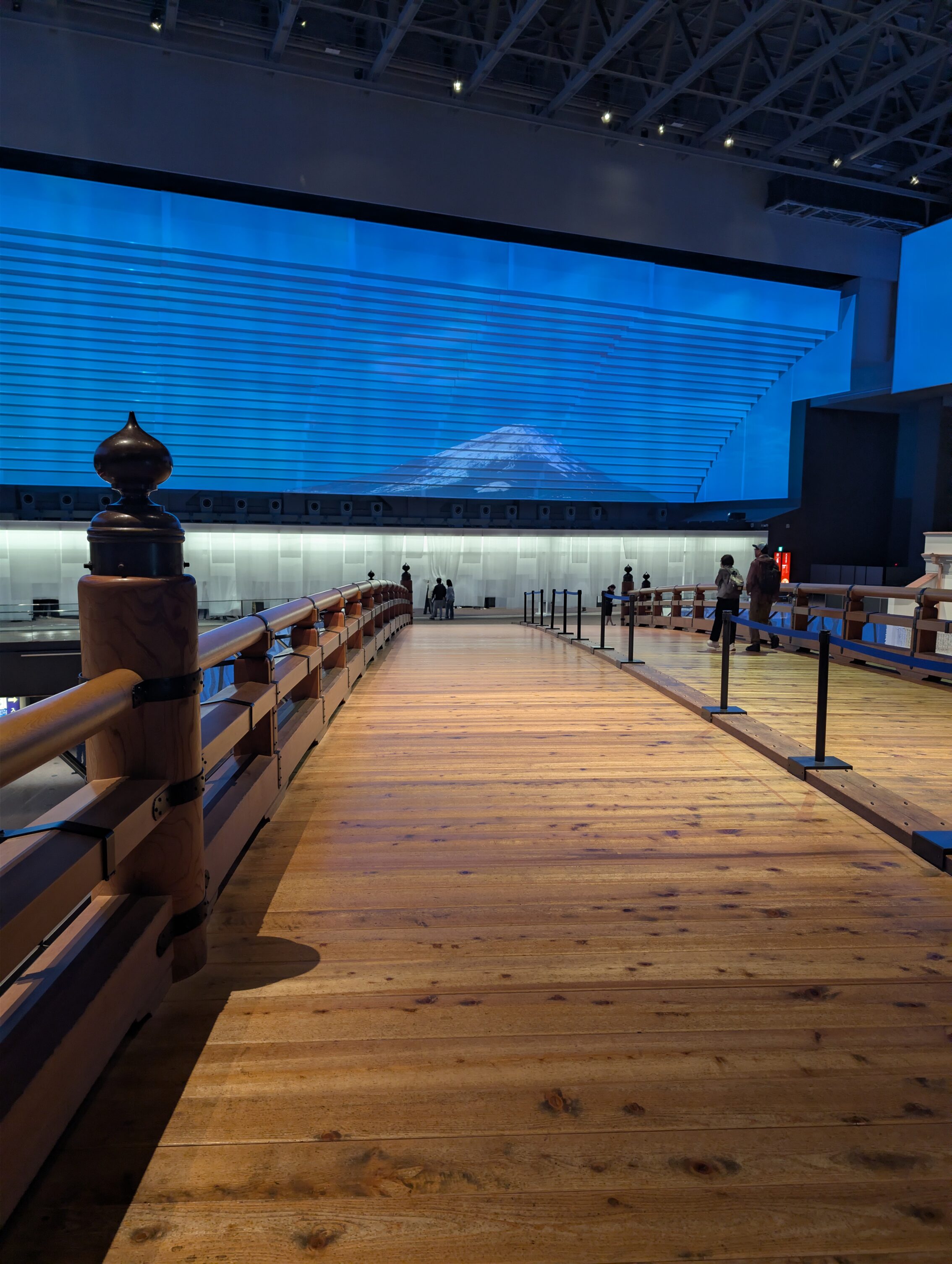 Wooden bridge in a museum, with a picture of Mount Fuji in the background.