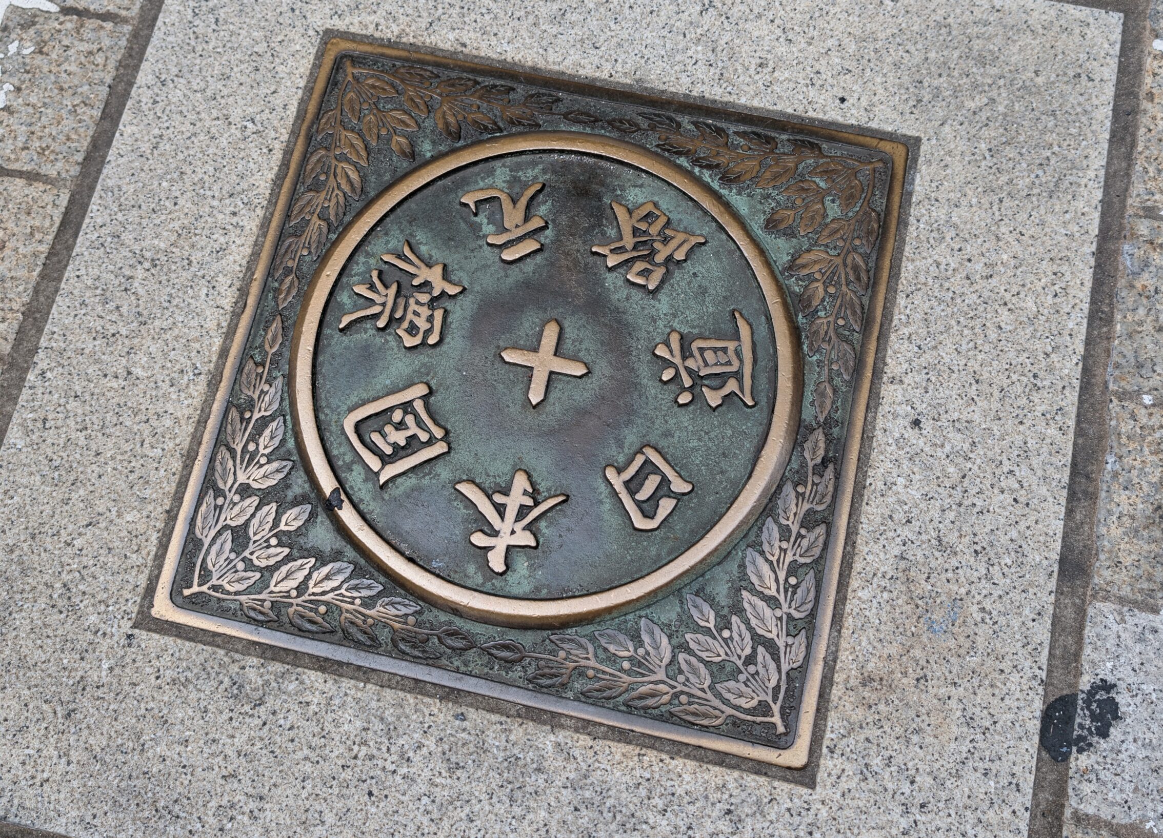 Metal plate in the road with inscriptions that it is the mark where all roads start.