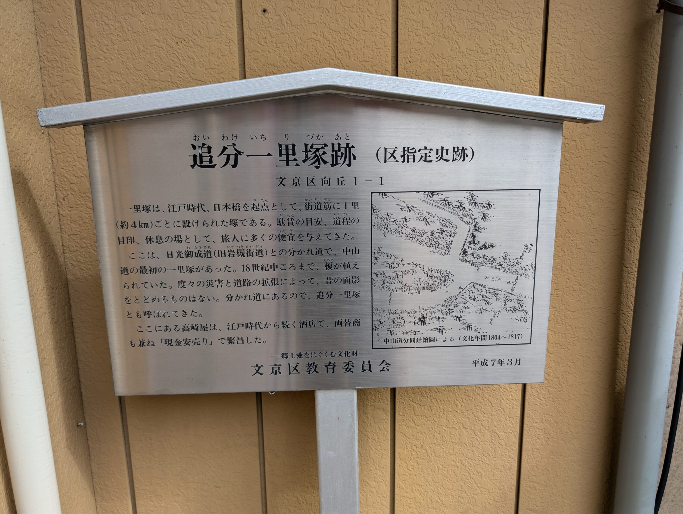 A metal plaque with text in Japanese about the milestone.