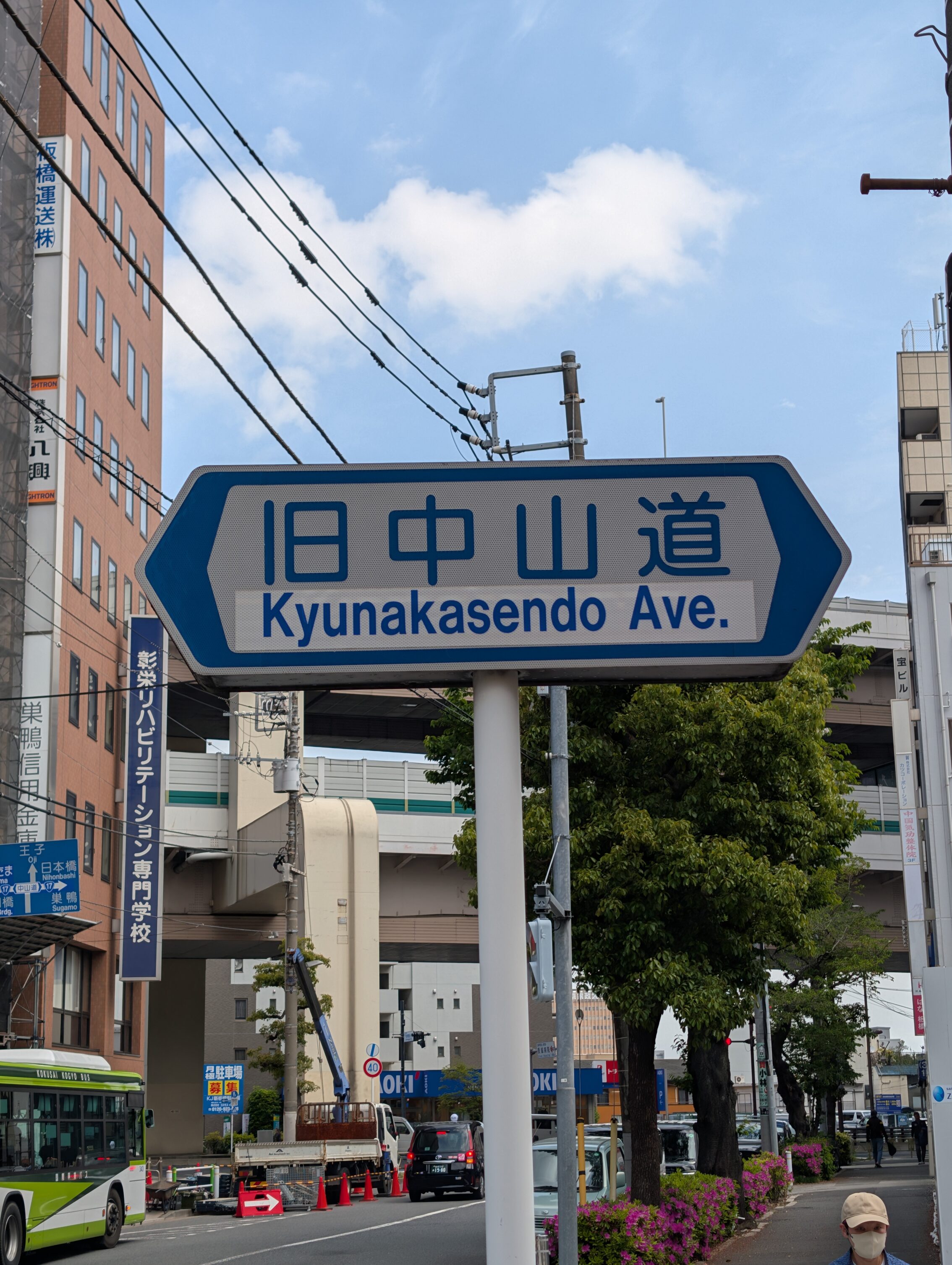 White sign with blue border and blue text, mounted on a meral pole.