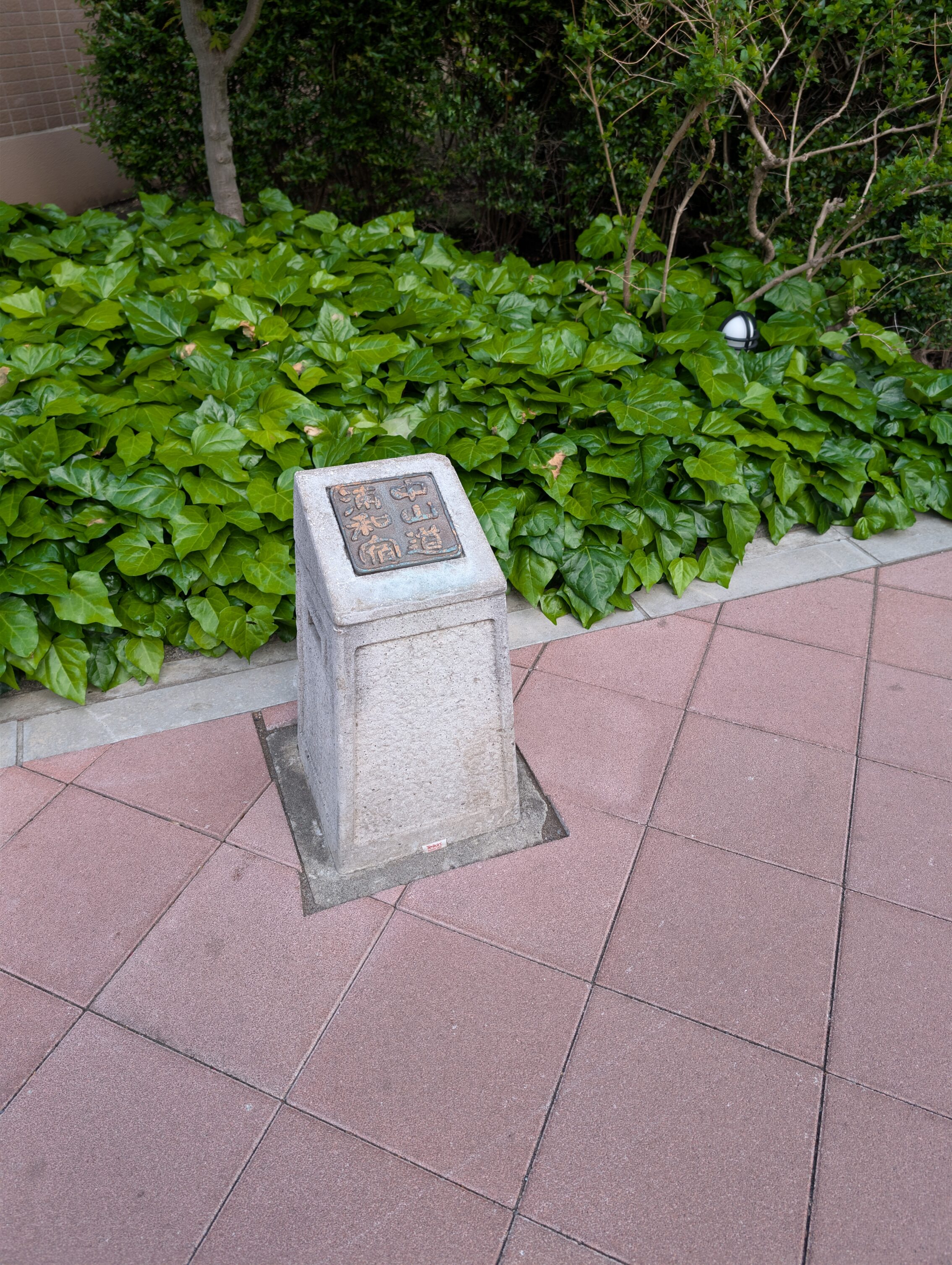 Small stone marker, maybe 30-40 cm high with a bronze plaque on top.