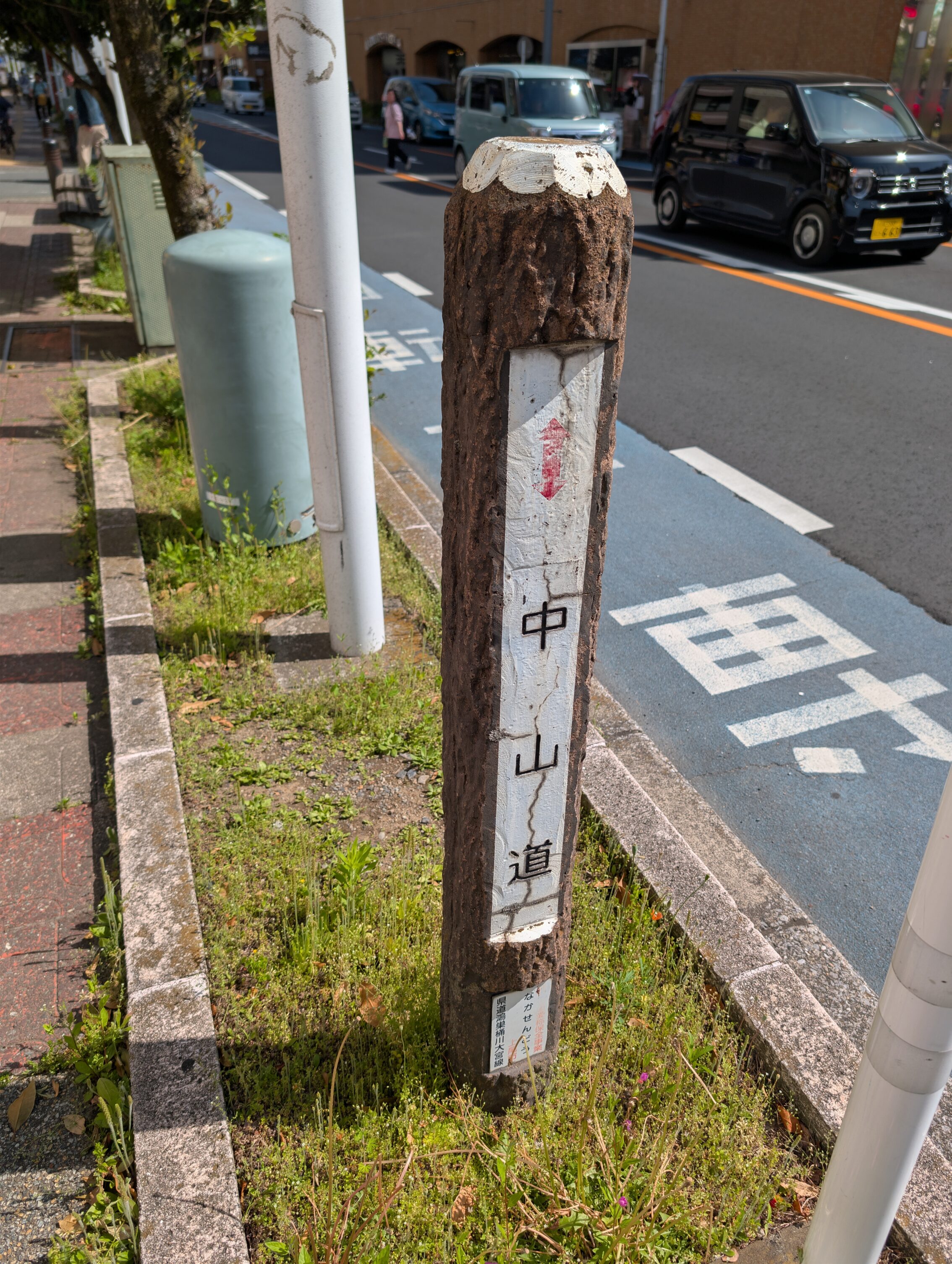 A cement pole made to look like a log, with a white horisontal section with black text. 