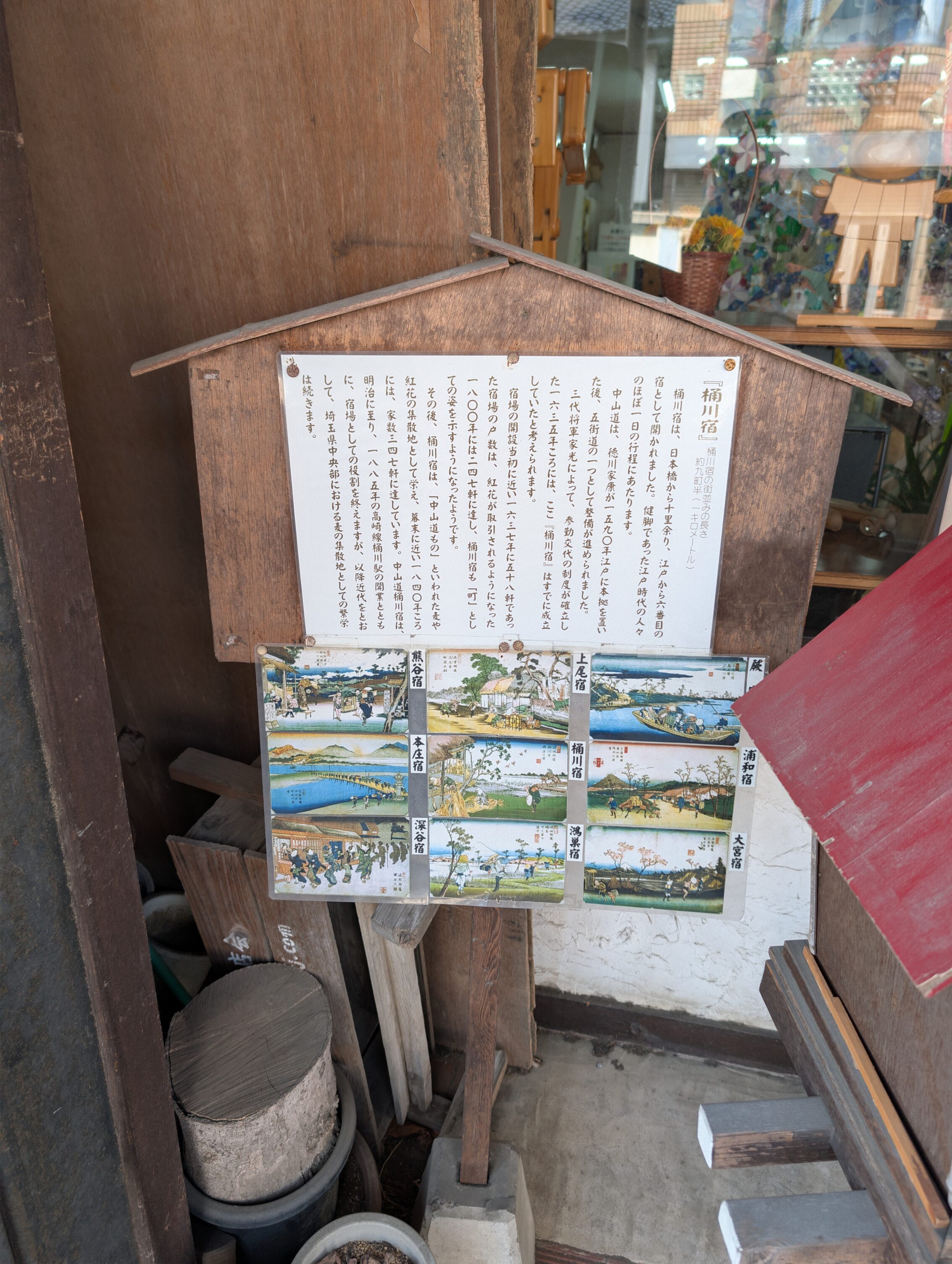 A wooden sign with post cards mounted beneath.