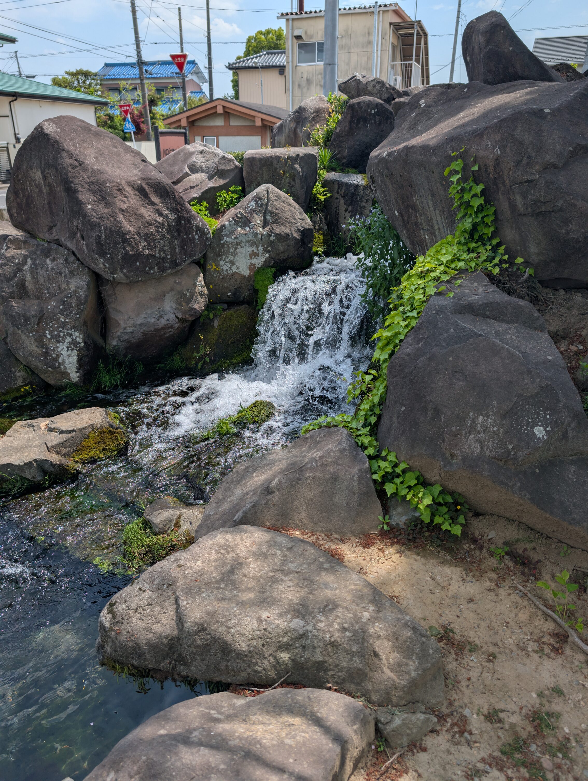 A small waterfall with large rocks surrounding it.