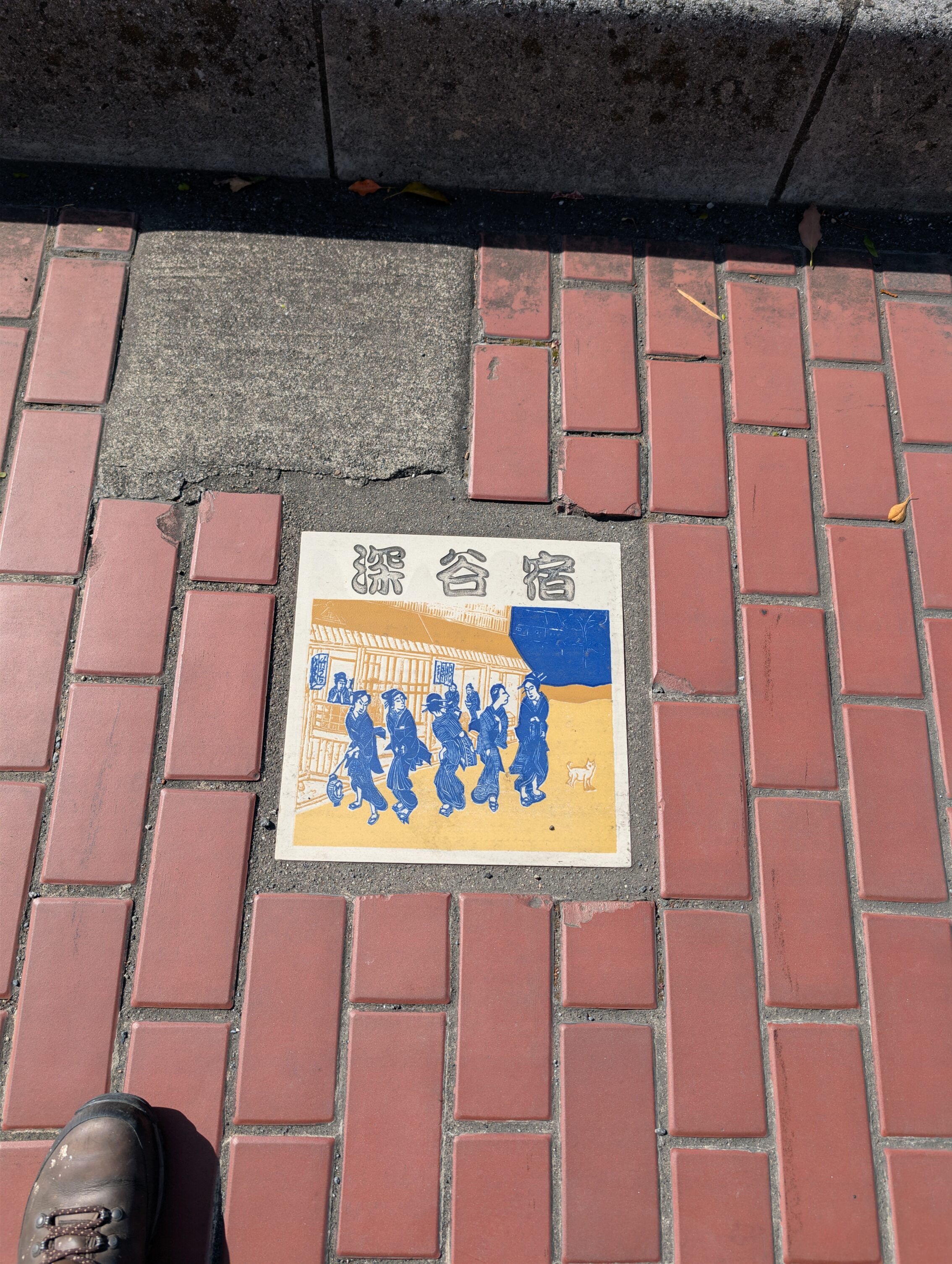 A brick pavement with a coloured tile depicting Fukaya-shuku.