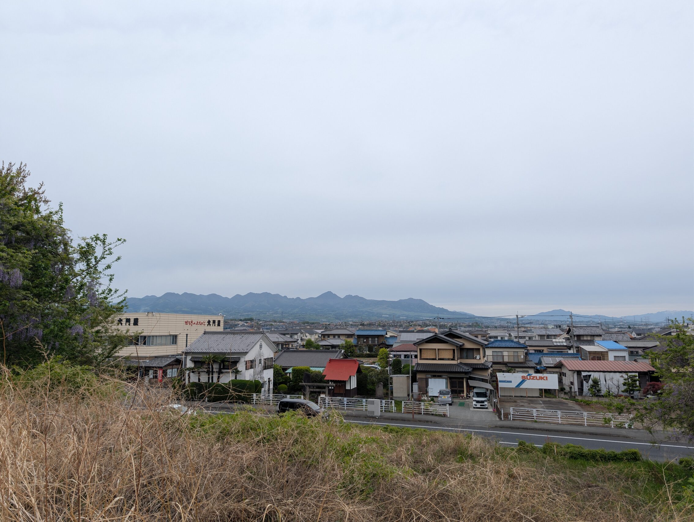 A village in the distance, with blueish mountains even further away.