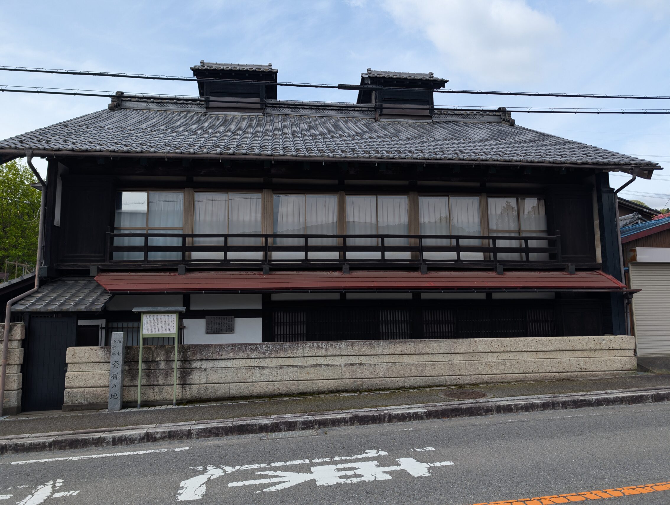 A black wooden building with two floors at the side of the road.
