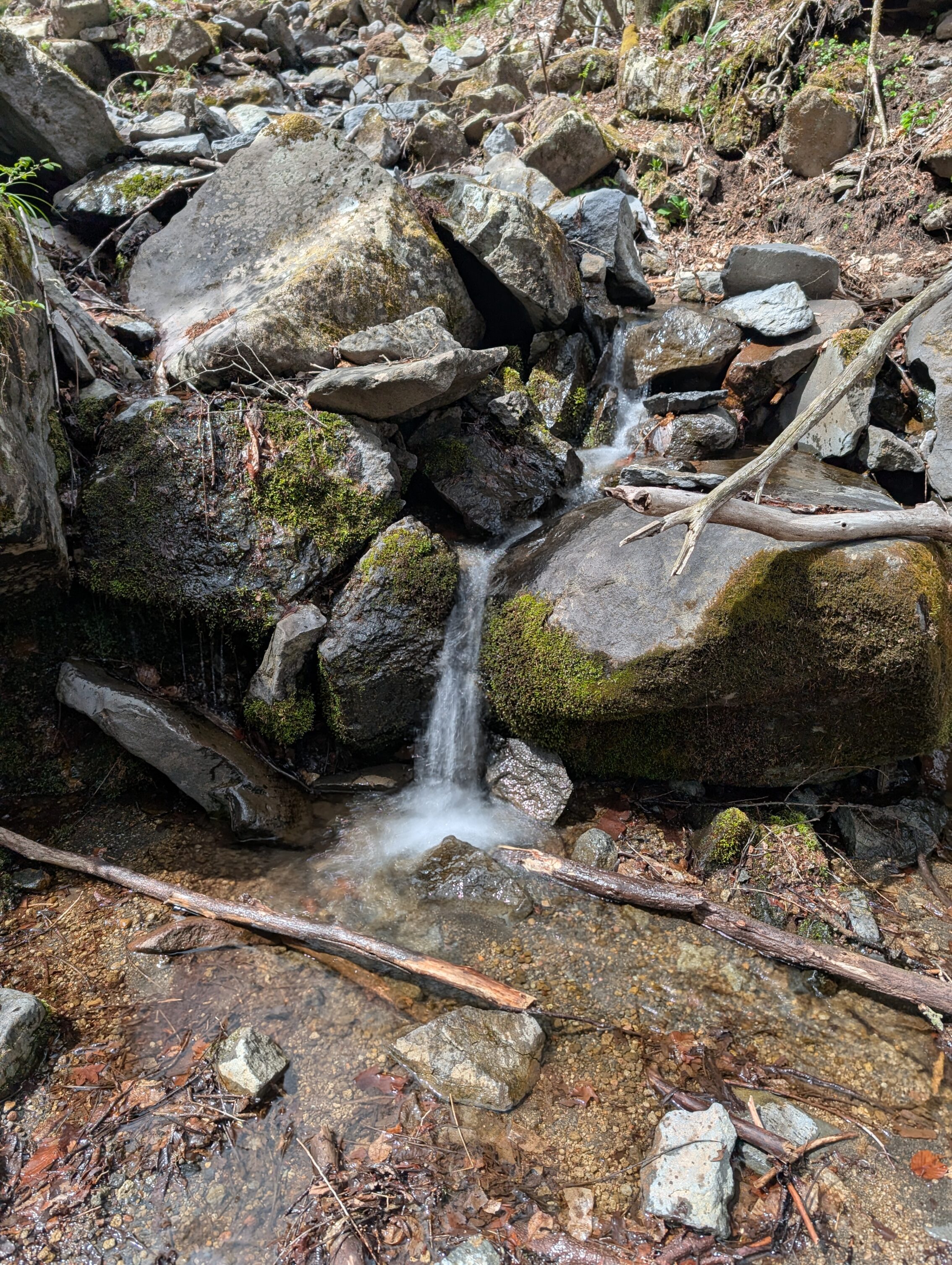 A long exposure photo of a small stream running between a couple of boulders.