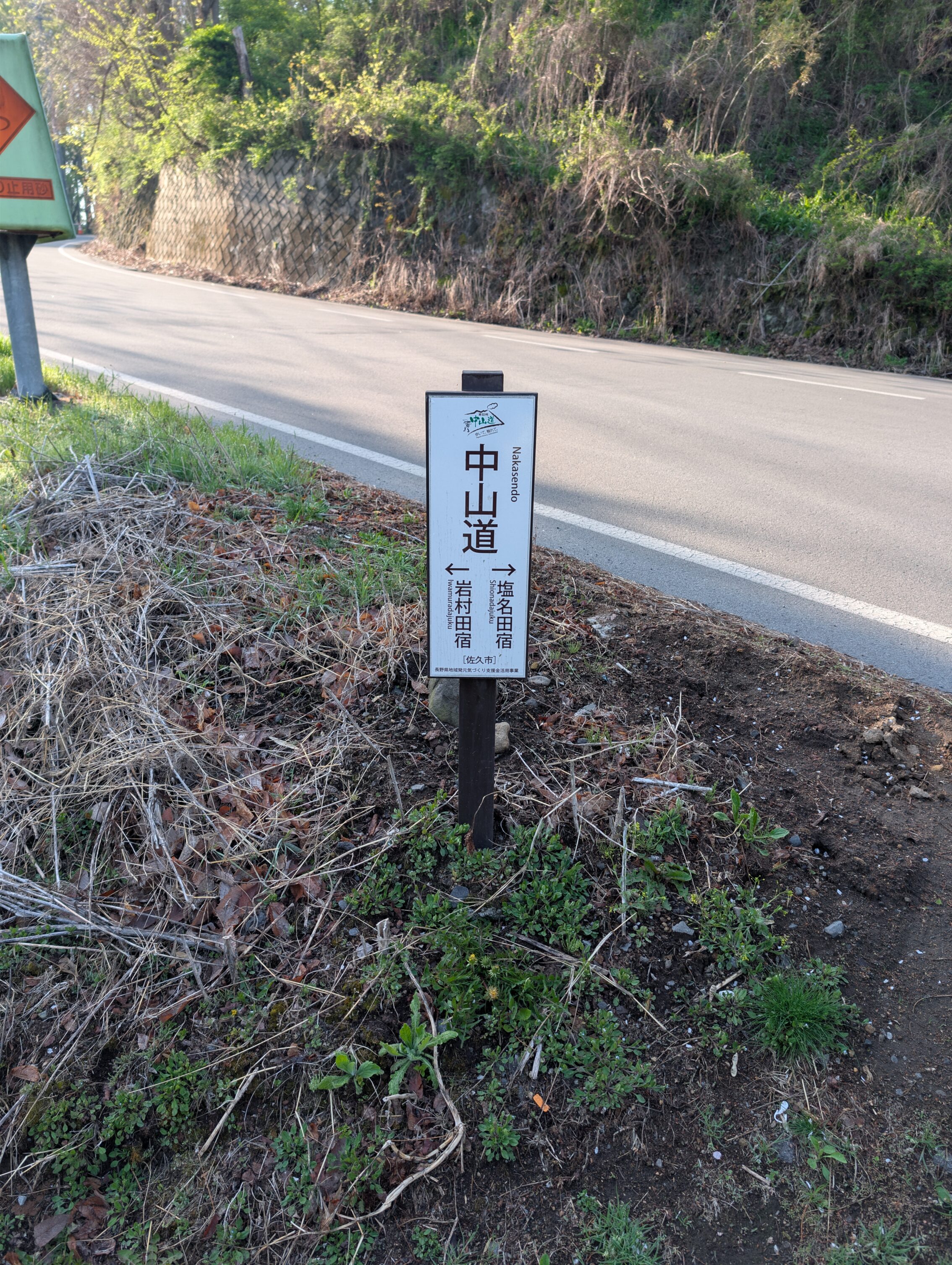 White sign, about a metre high oriented vertically with dark brown text and arrows pointing the way in both directions.