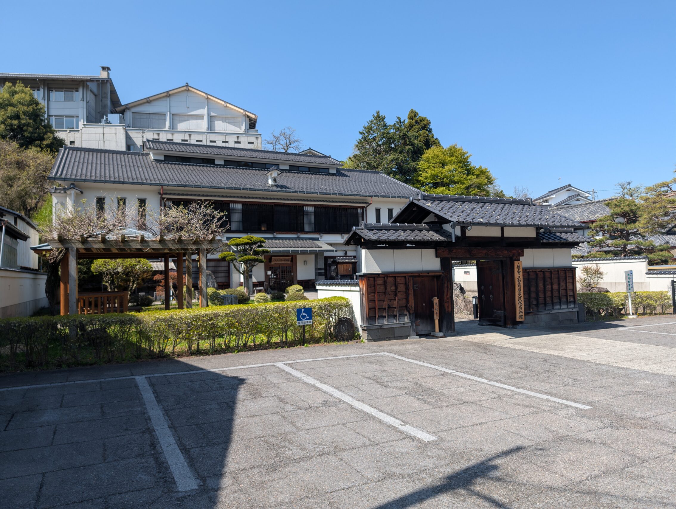 The remains of a honjin gate, in front of a parking lot. Behind the gate is a more modern building that houses a museum.