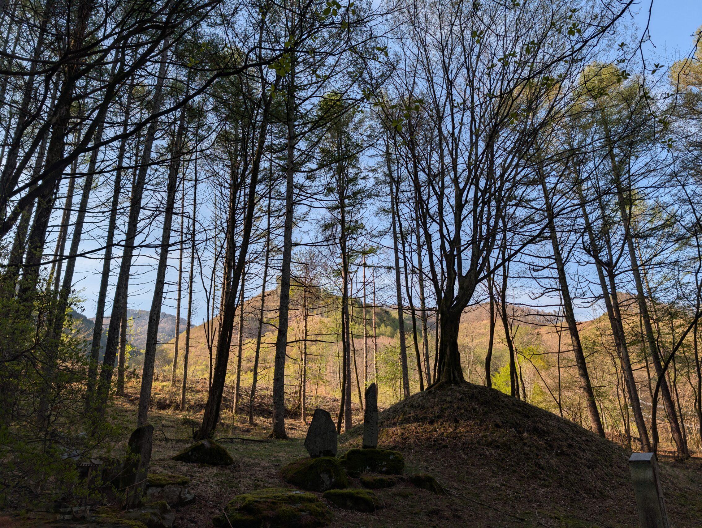 A milestone mound with trees and hills in the background.