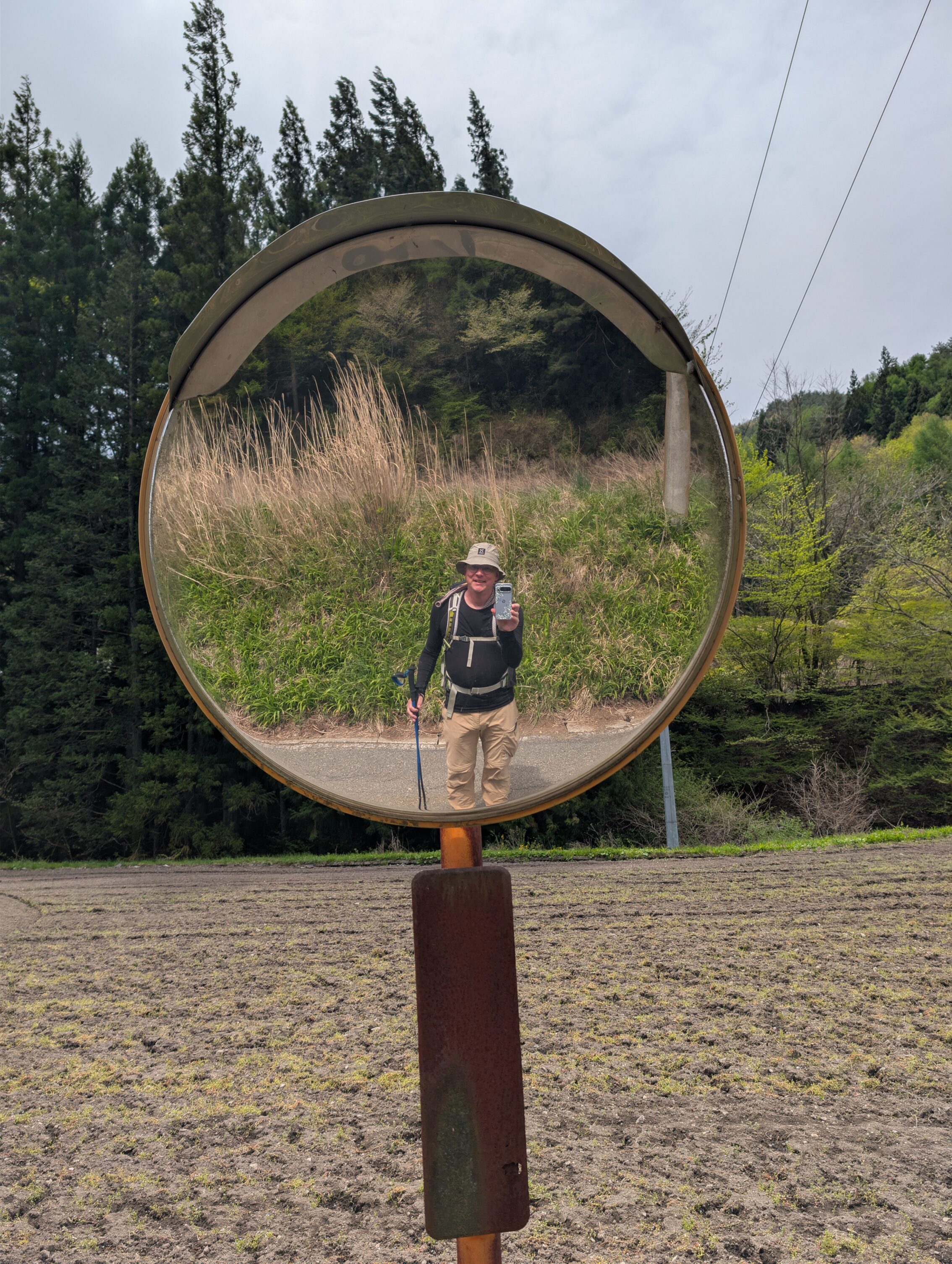 A mirror for seeing around a sharp corner as you are driving. The author is posing in the picture, and is seen in the mirror.