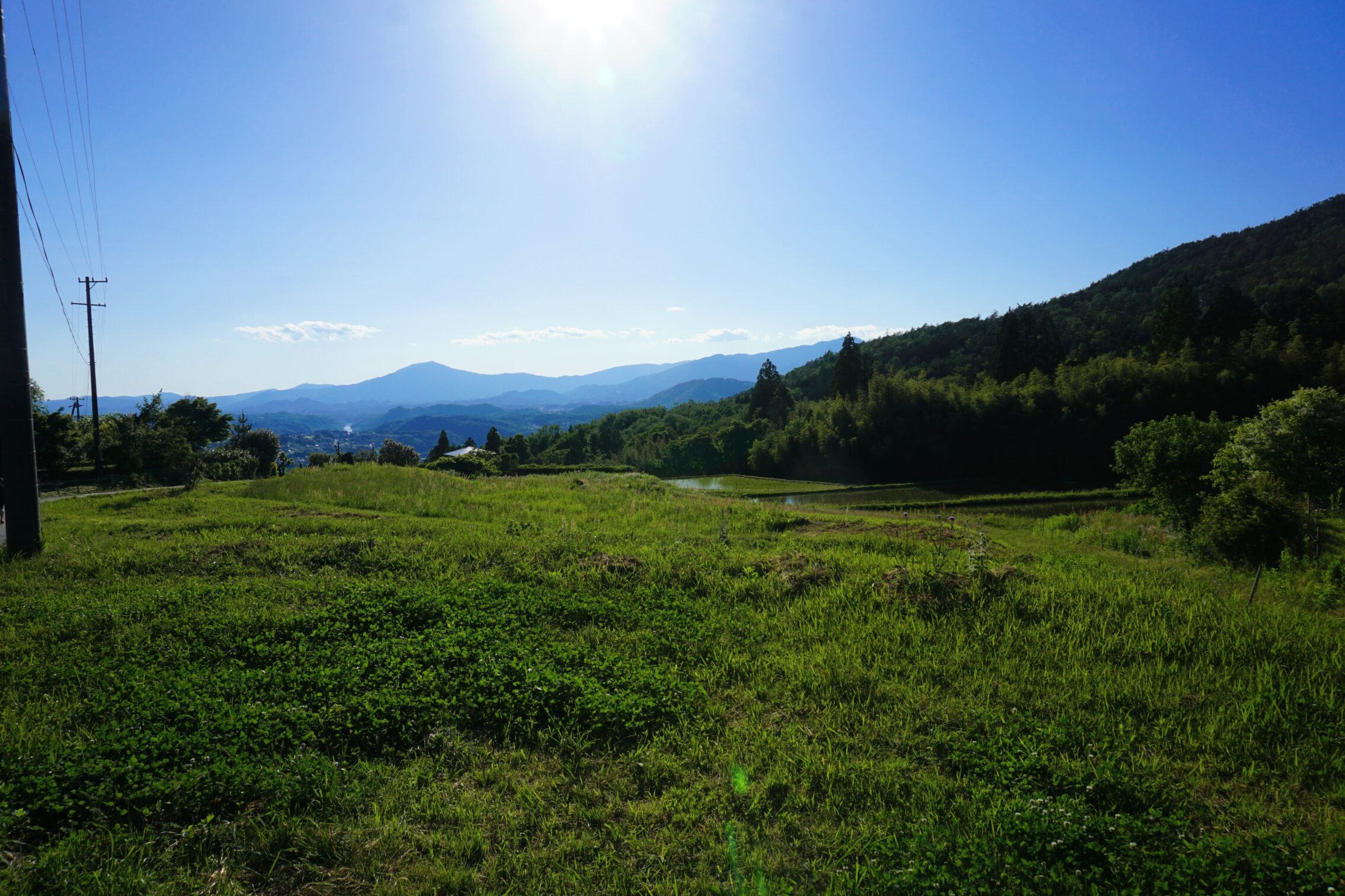 A view of mountains in the distance, with a blue sky and sun.