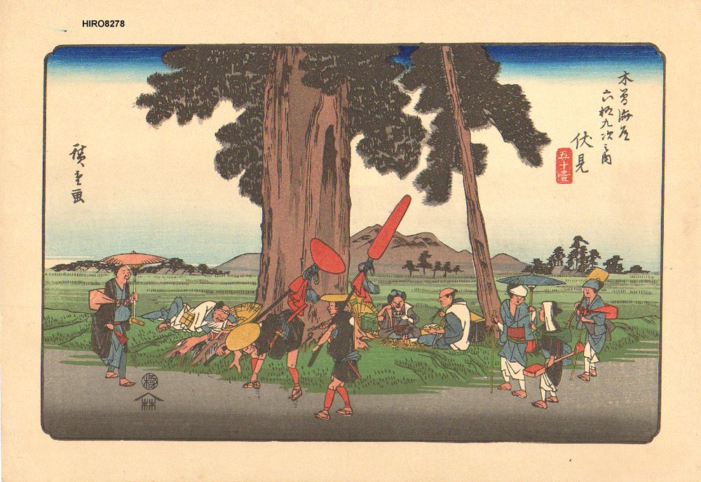 A number of travellers har hiking in both directions on a road, with a large tree in the background and mountains far away. There is also a few people sitting in the grass eating food.