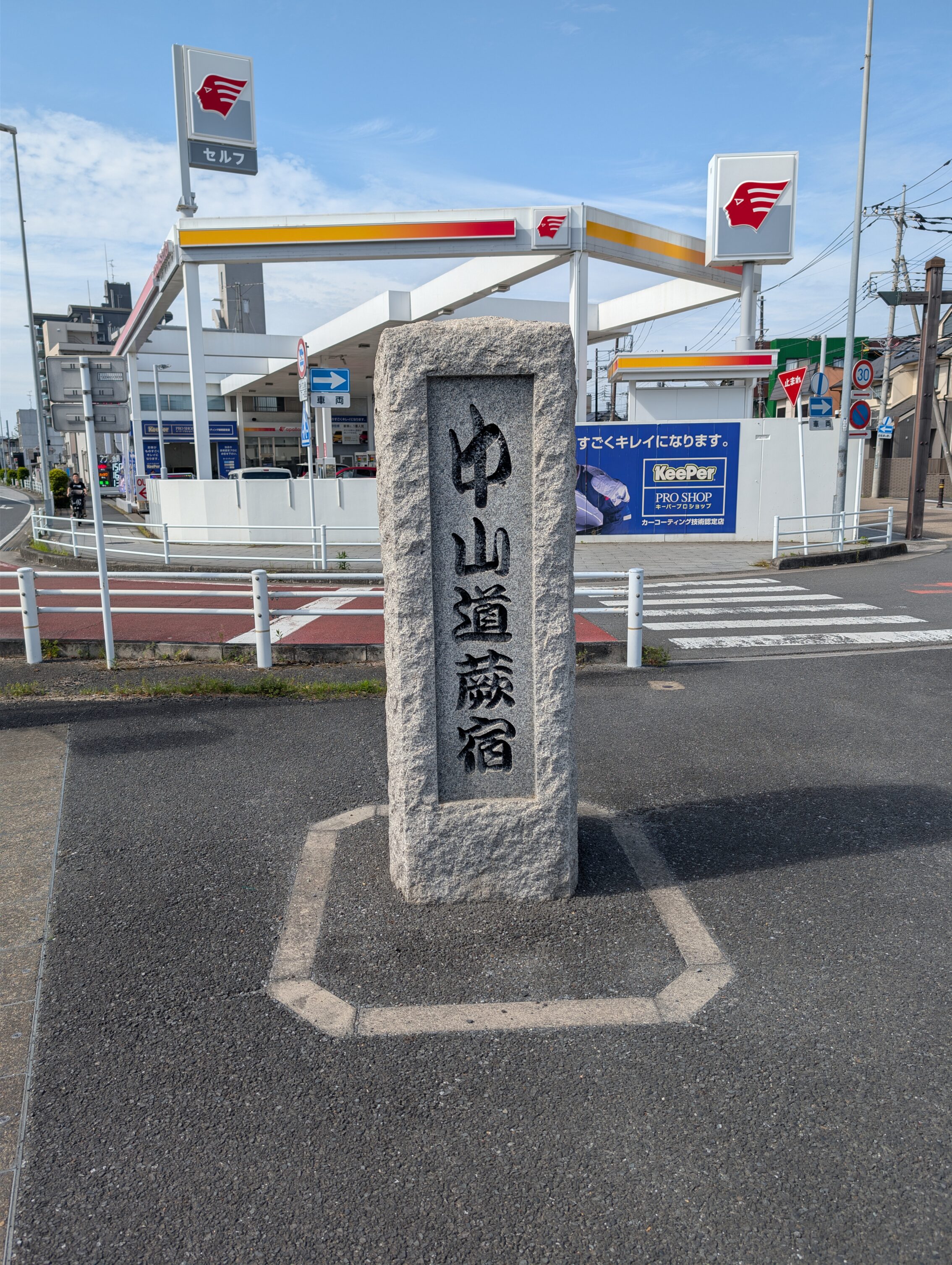 A standing stone in the middle of a refuge, inscribed with the words "Nakasendō Warabi-shuku" in Japanese.