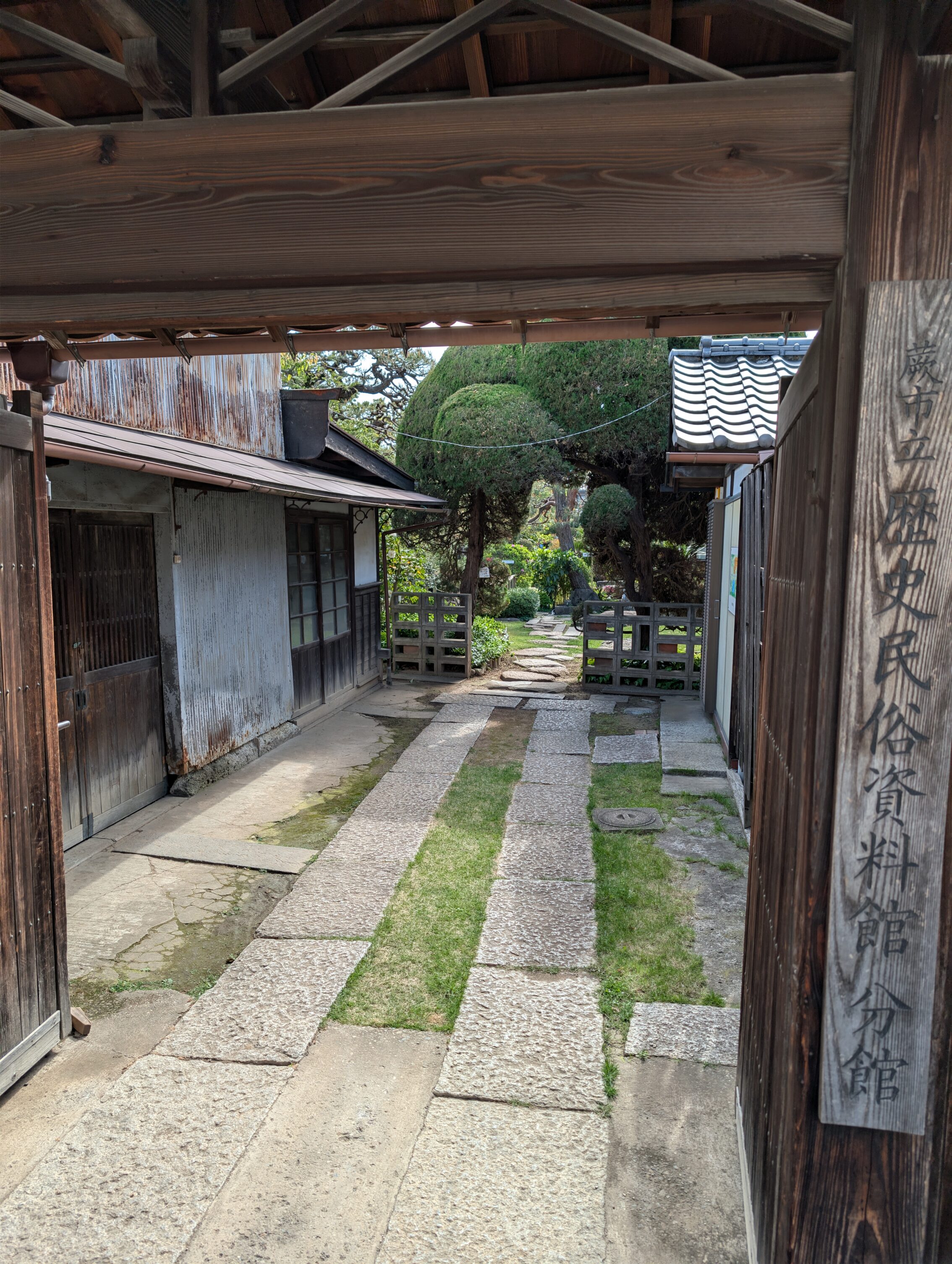 Entrance gate, with wooden houses on both sides of a corridor, leading to the garden.