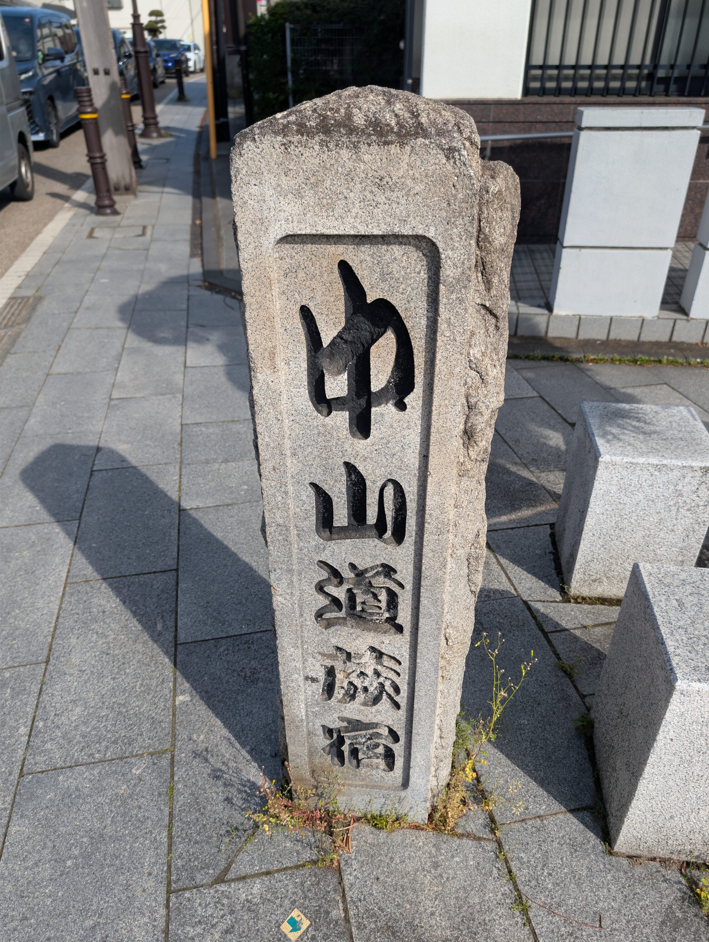 A standing stoneat the side of the road, inscribed with the words "Nakasendō Warabi-shuku" in Japanese.