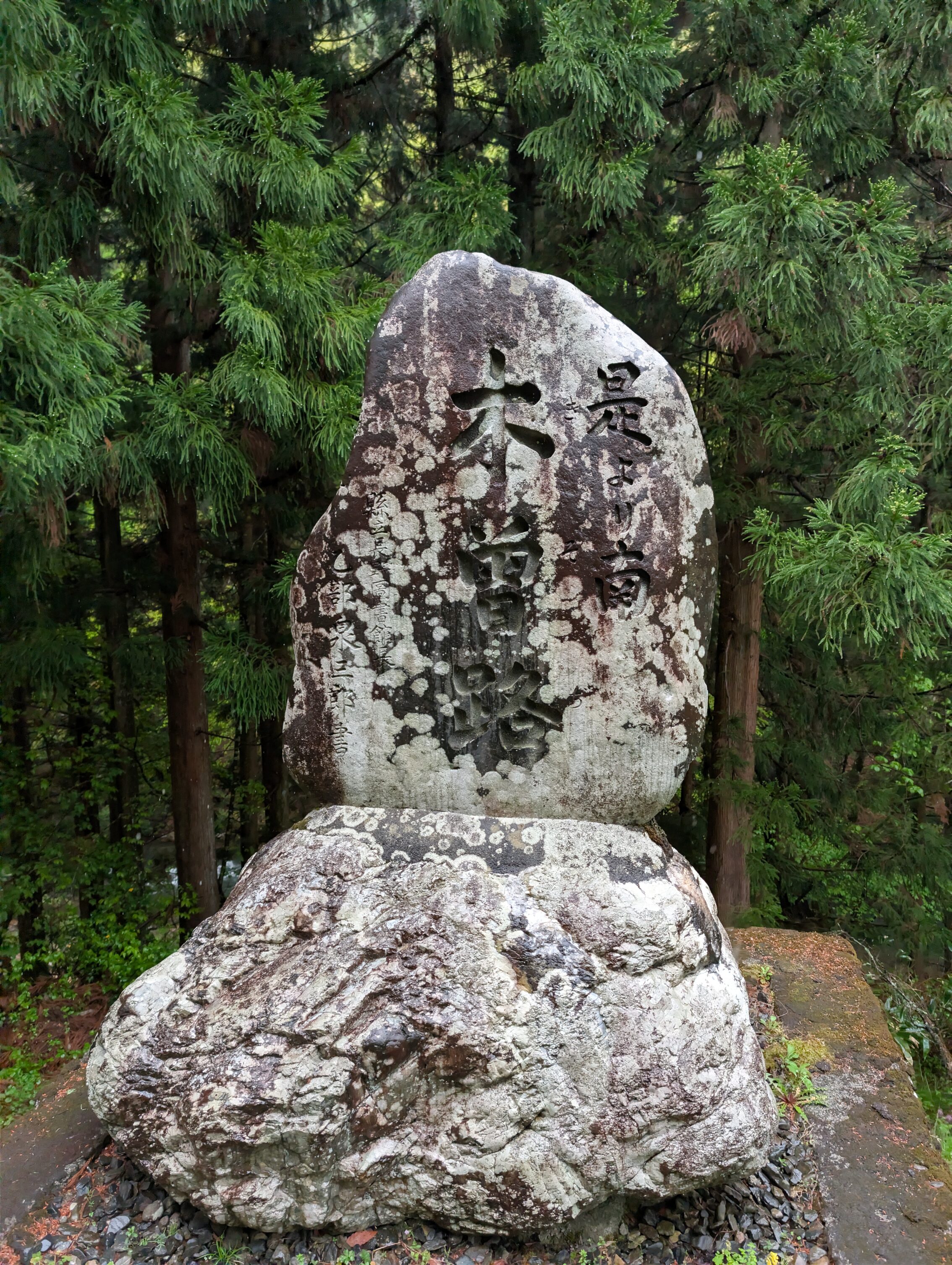 A large stone marker with Japanese carvings.