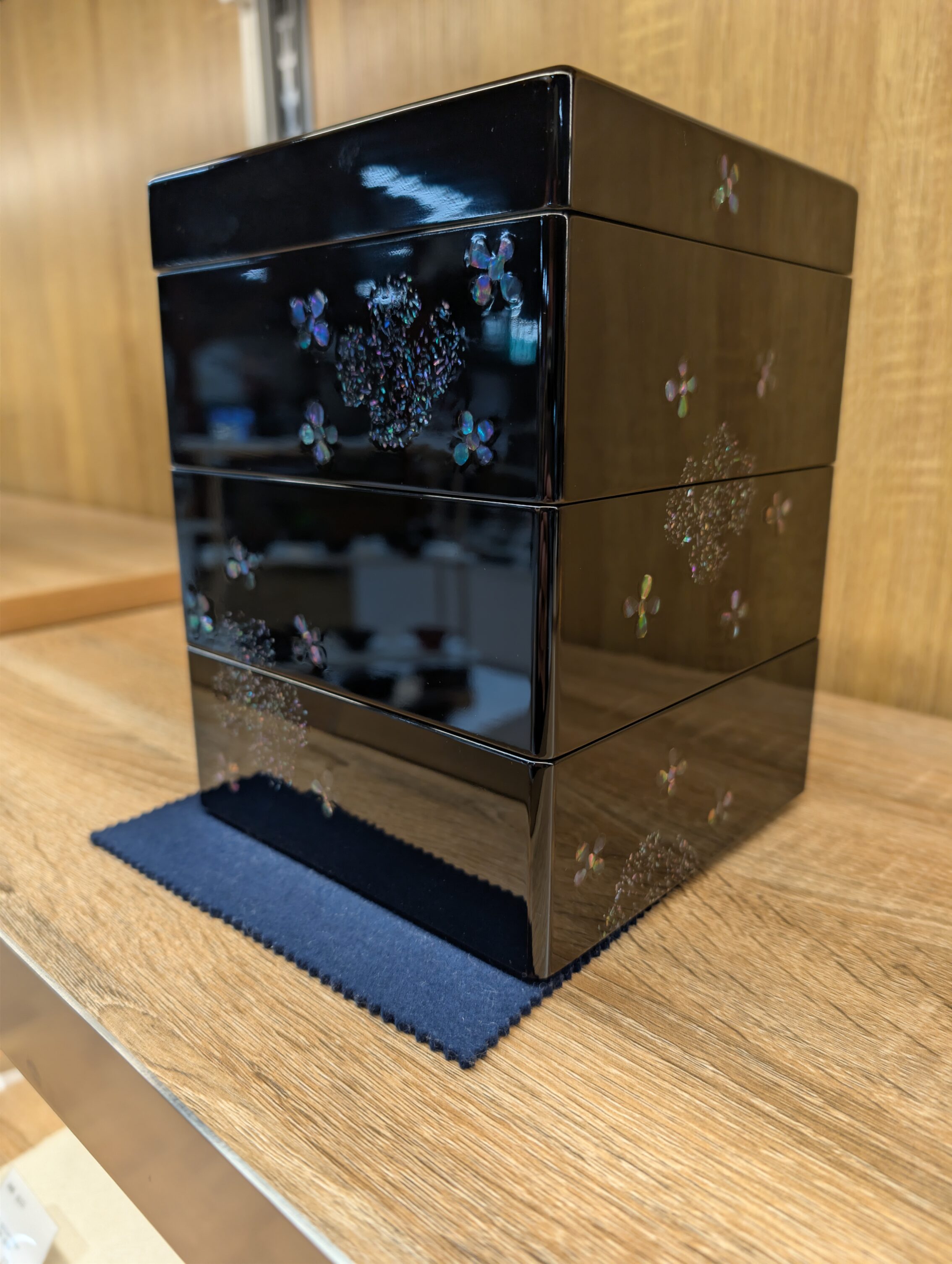 A small black cabinet with different layers of boxes, in urushi.