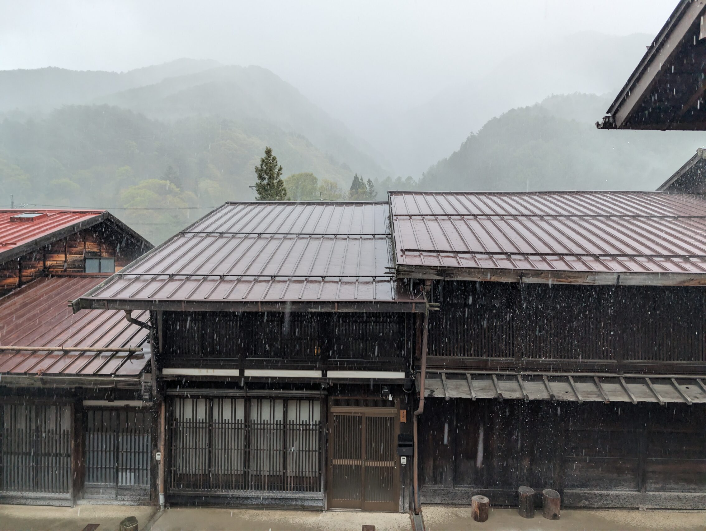 An Edo period house from across the street, with visible rain pouring down.