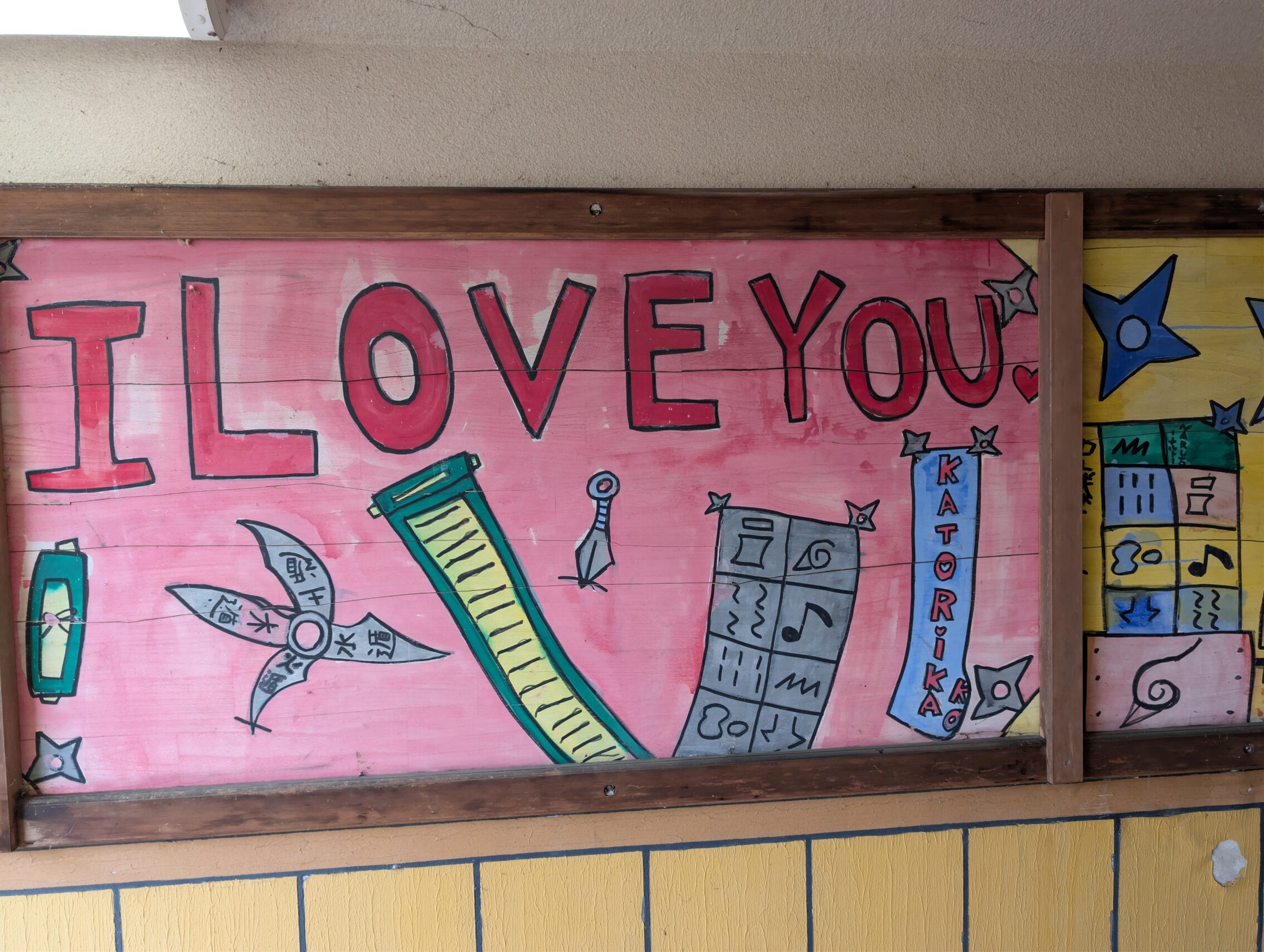 A kid's drawing in a subway tunnel, with the text in pink letters "I LOVE YOU", and lots of weapons.
