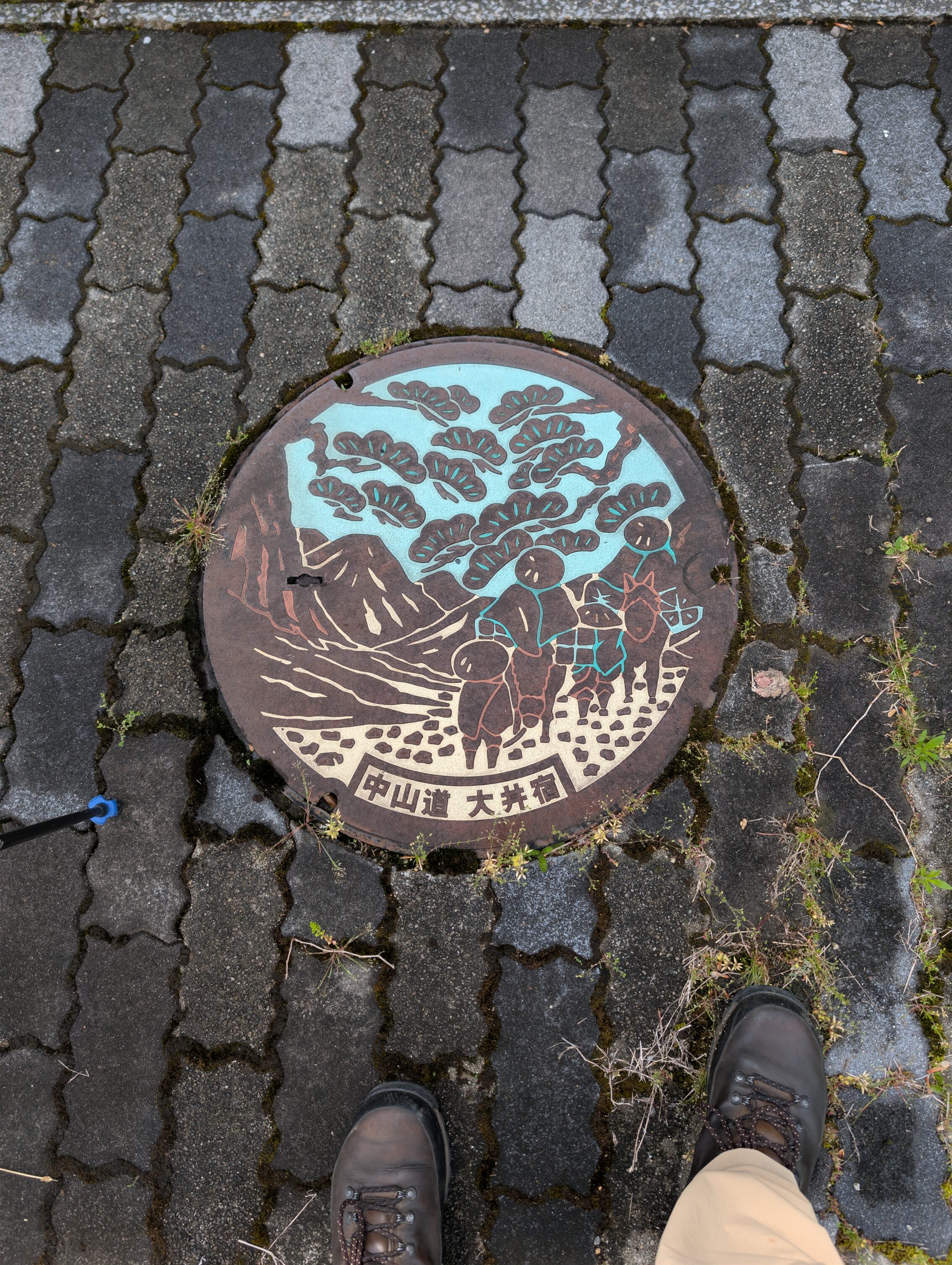 Manhole cover showing three Edo period travellers in the wilderness.