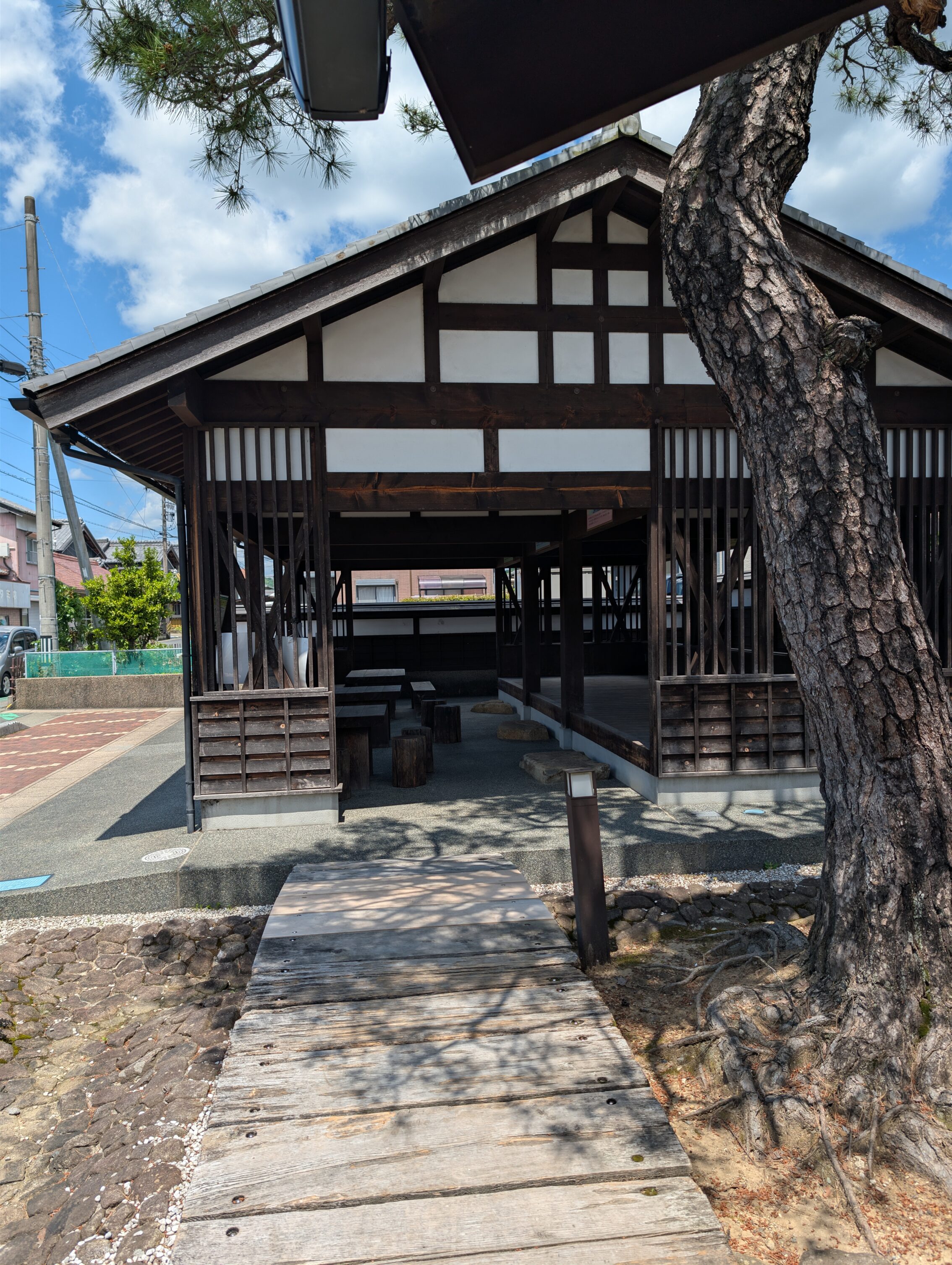 A single tree in front of an open hut.