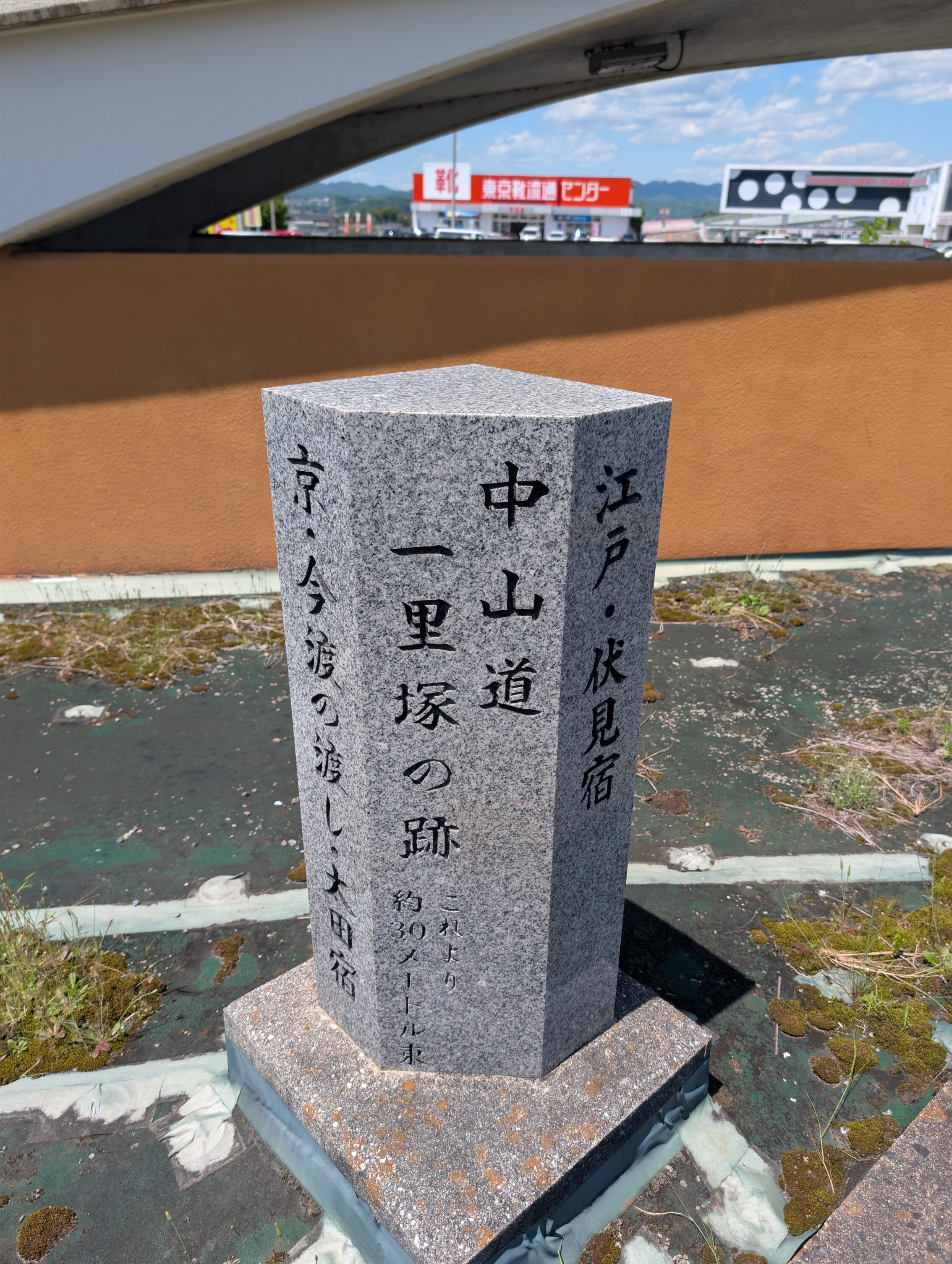 A modern milestone marker in stone with japanese text in black.
