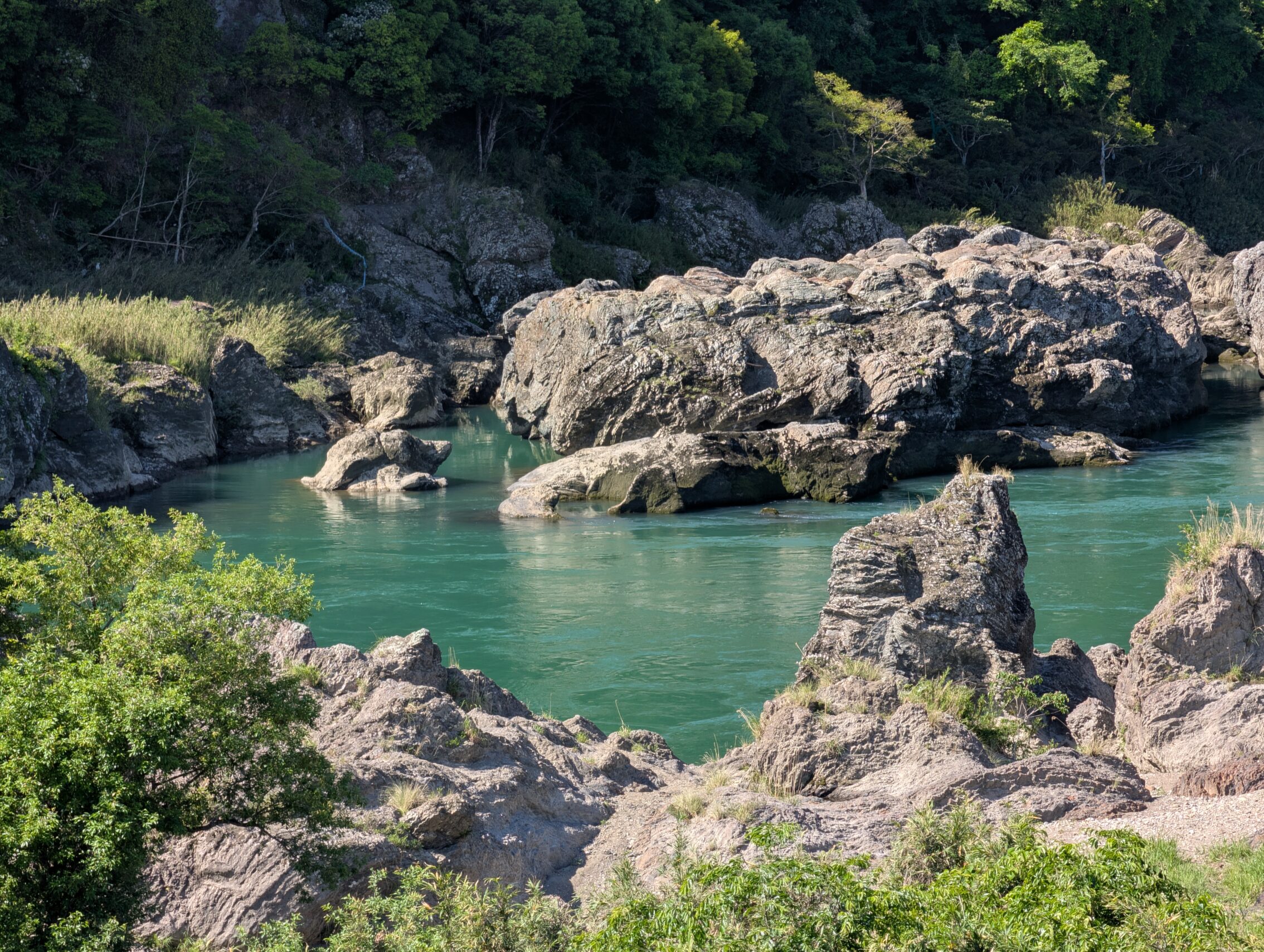 A close-up of the Kiso river as it passes some jagged rocks.