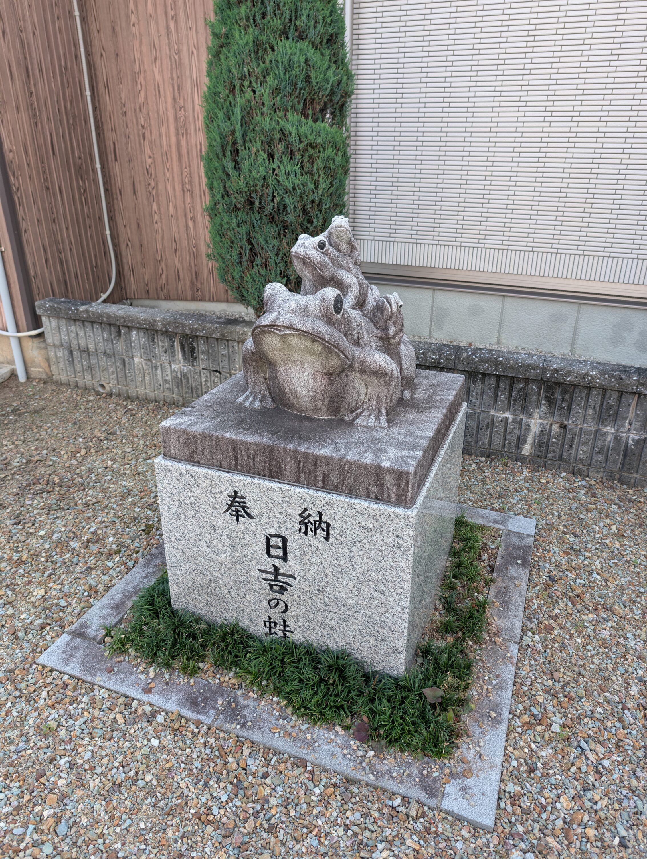 A square stone foundation with a statue of a number of frogs climbing on top of each other.