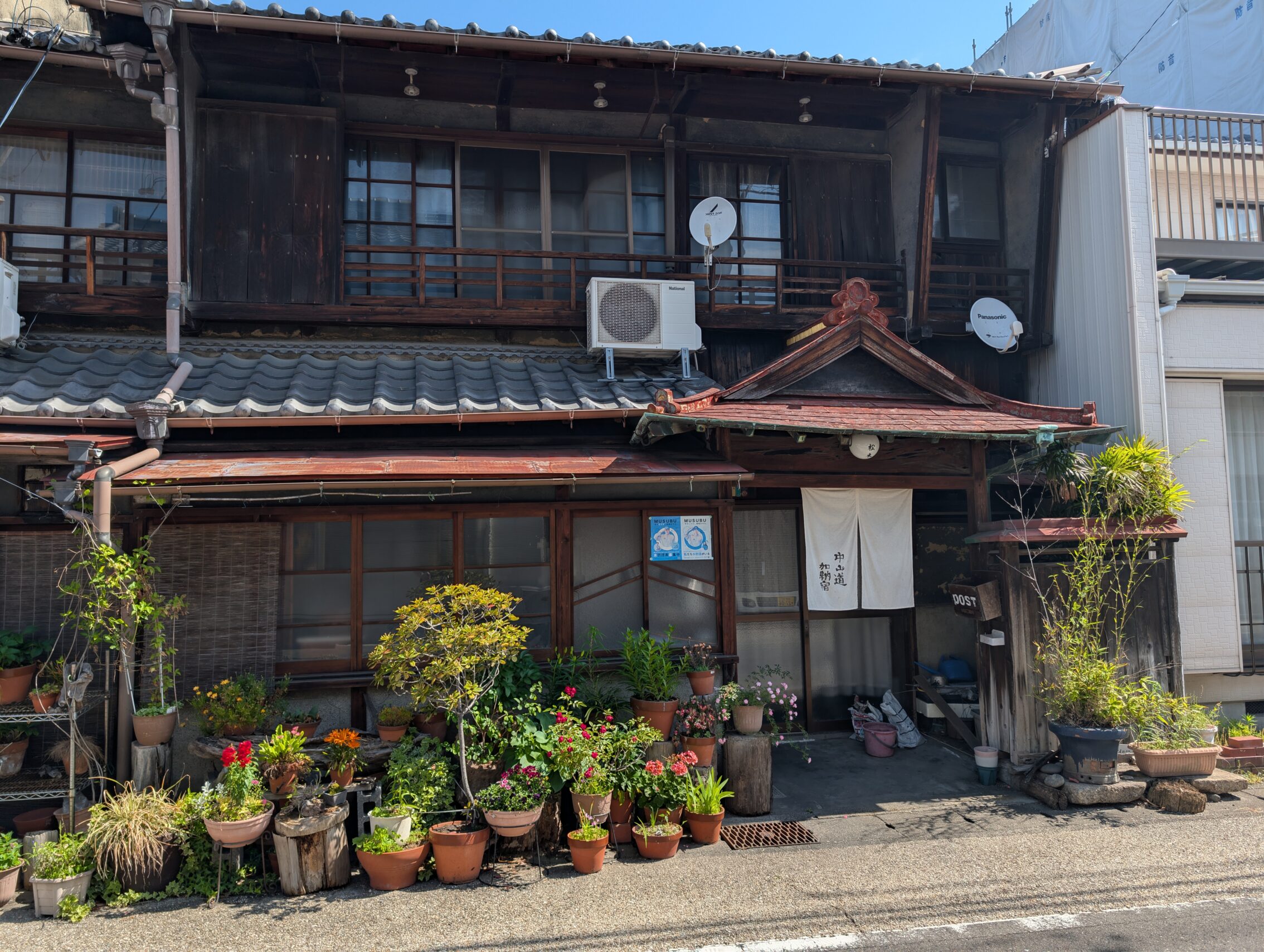 An old Edo period house with a lot of flower pots outside.