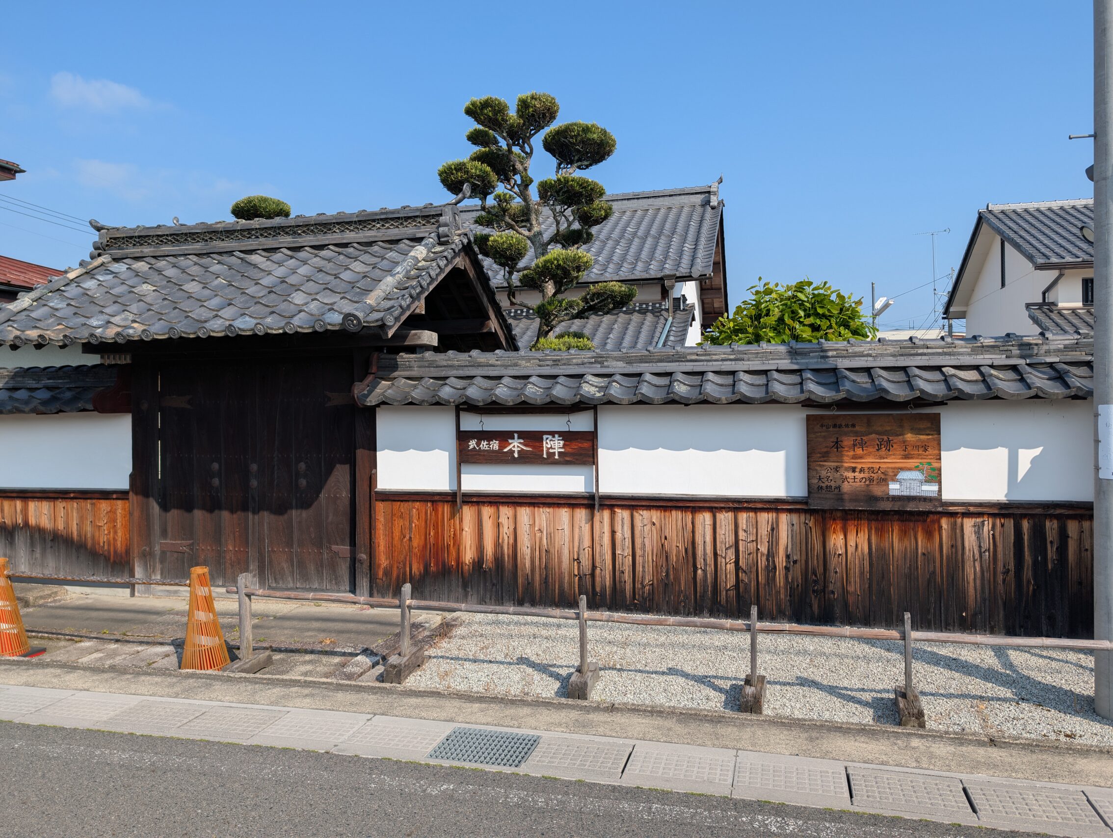 A white wall with wooden features, as well as a wooden gate with a roof.