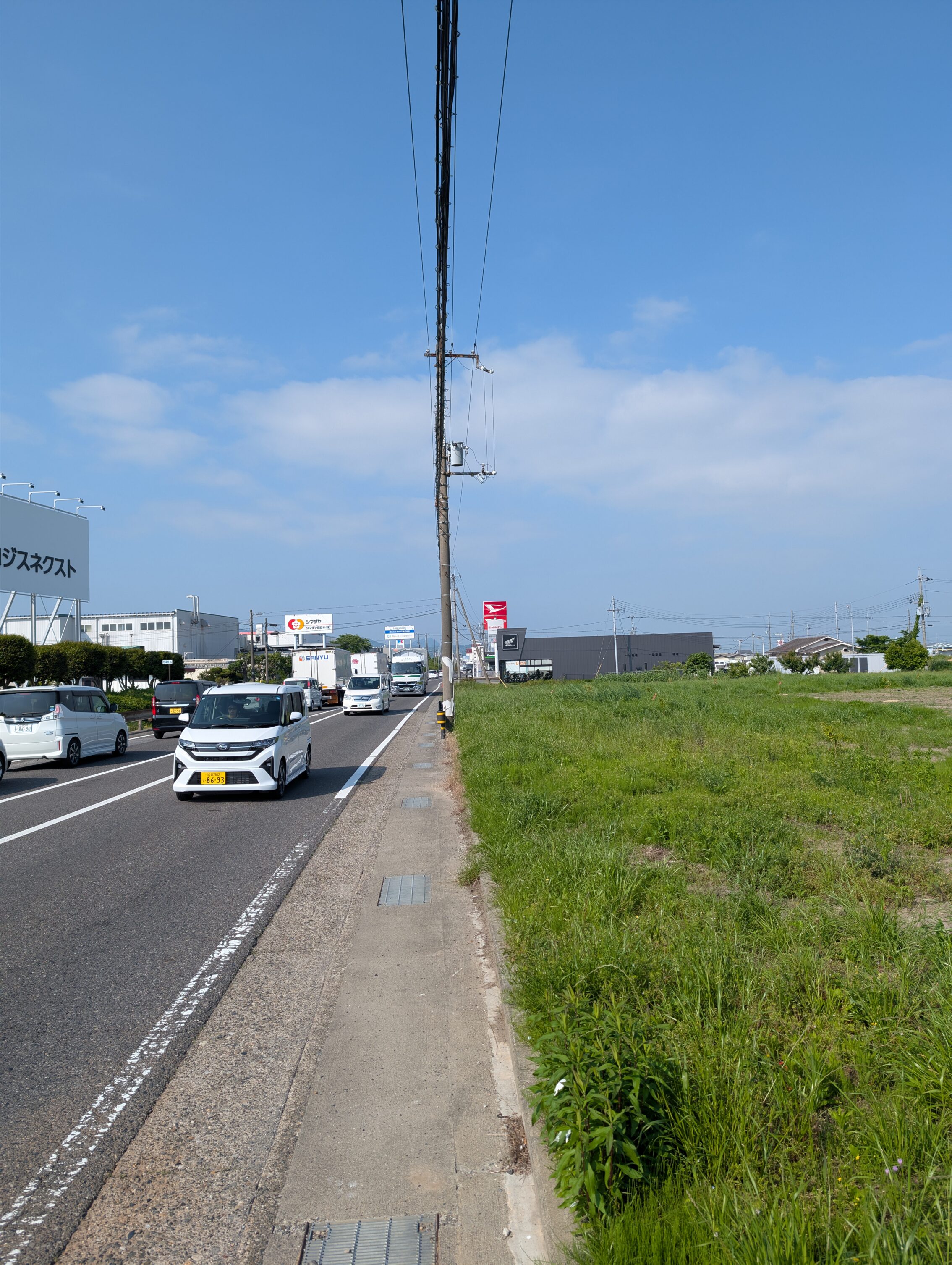 A large highway with incoming traffic and very little shoulder to walk on.