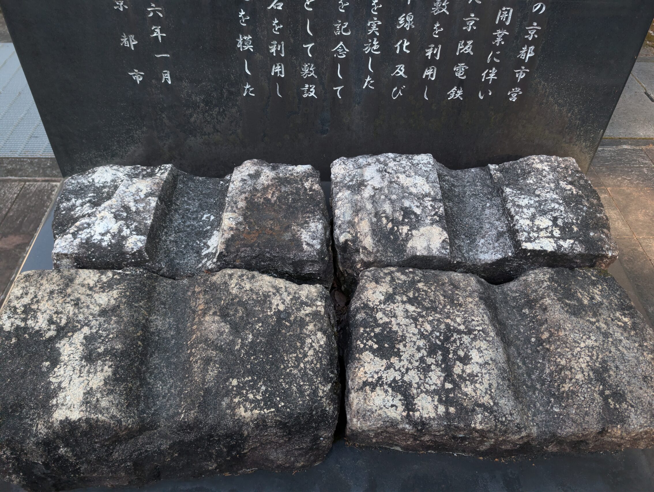 Part of an information board, and four stones showing carved wheel tracks.