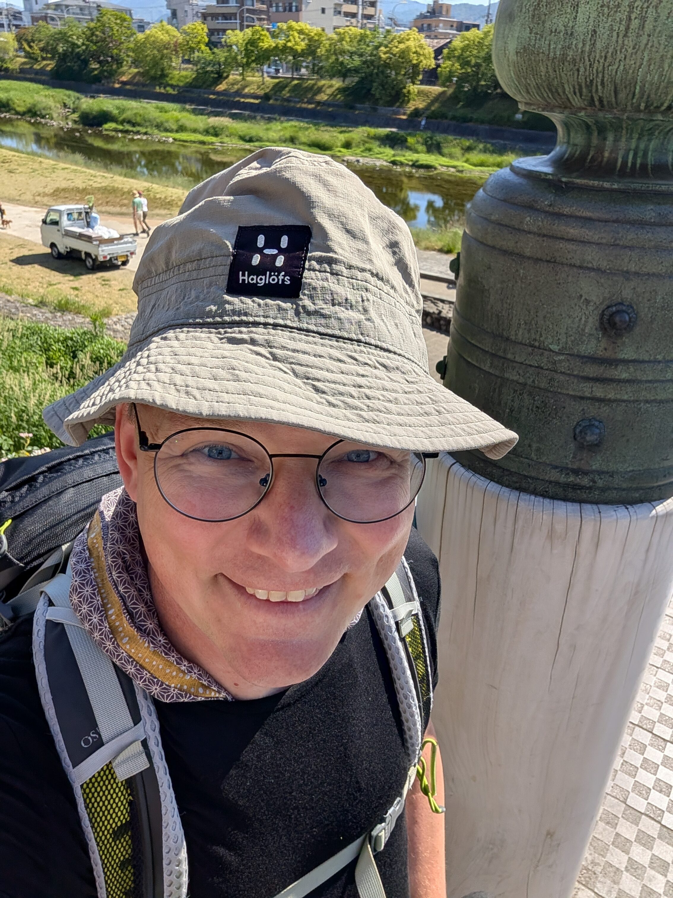 A happy hiker on a bridge above a river.