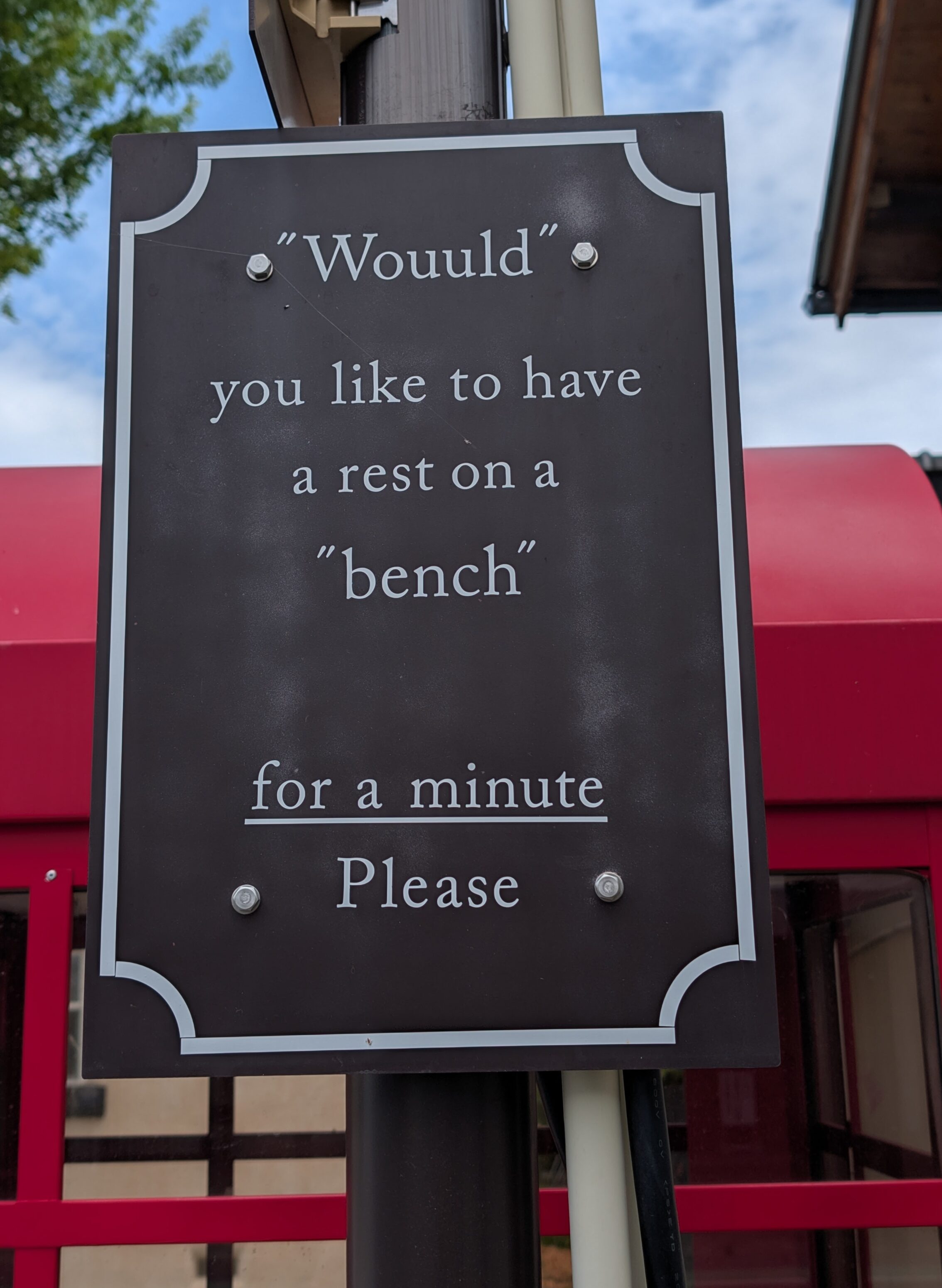 A sign with the text "Wouuld" you like to have a rest on a "bench" for a minute Please.