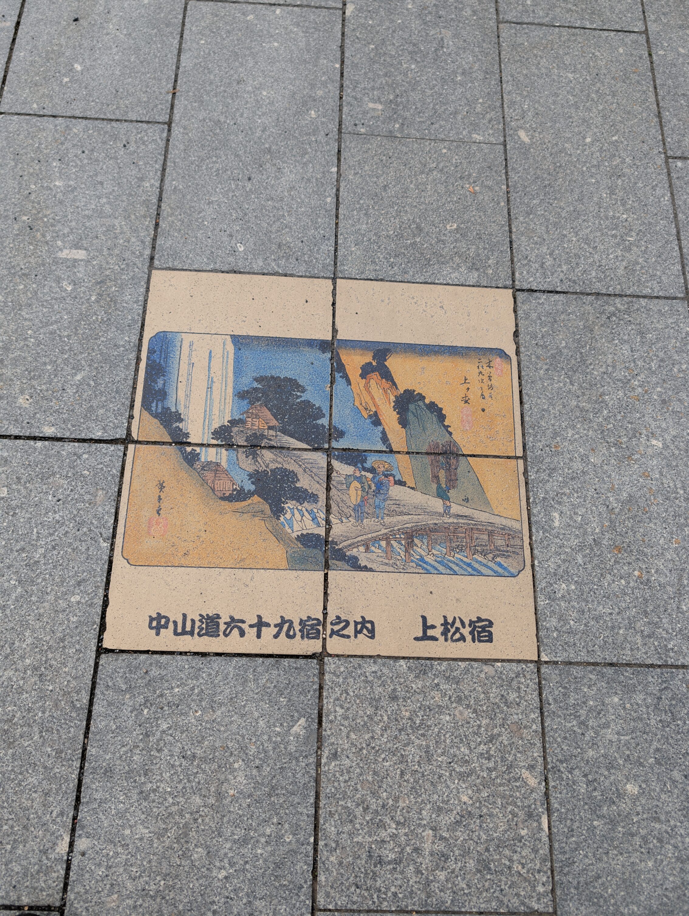 Coloured tiles in the pavement showing a scene from the book 69 Stations of the Kisokaido.