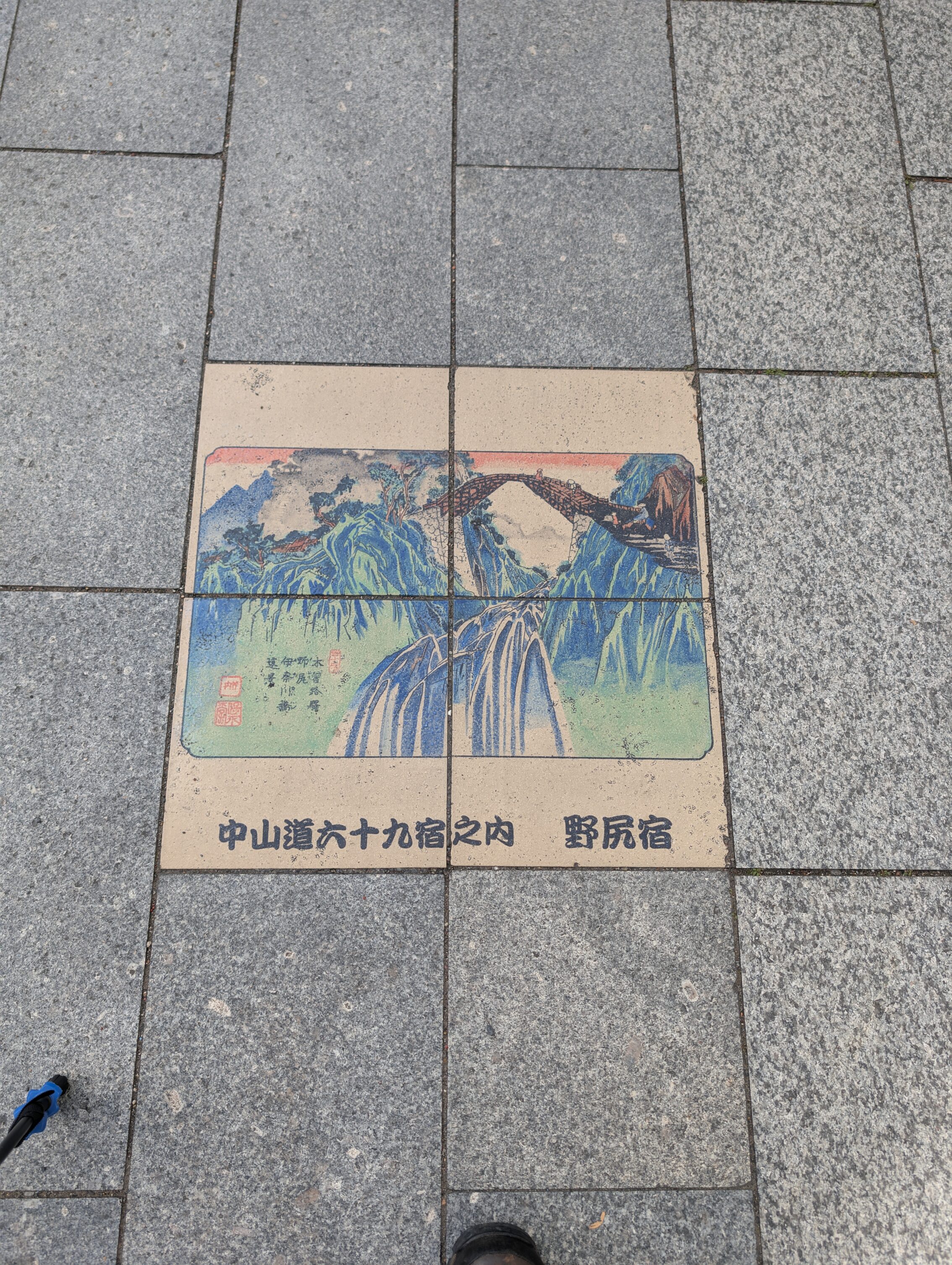 Coloured tiles in the pavement showing a scene from the book 69 Stations of the Kisokaido.