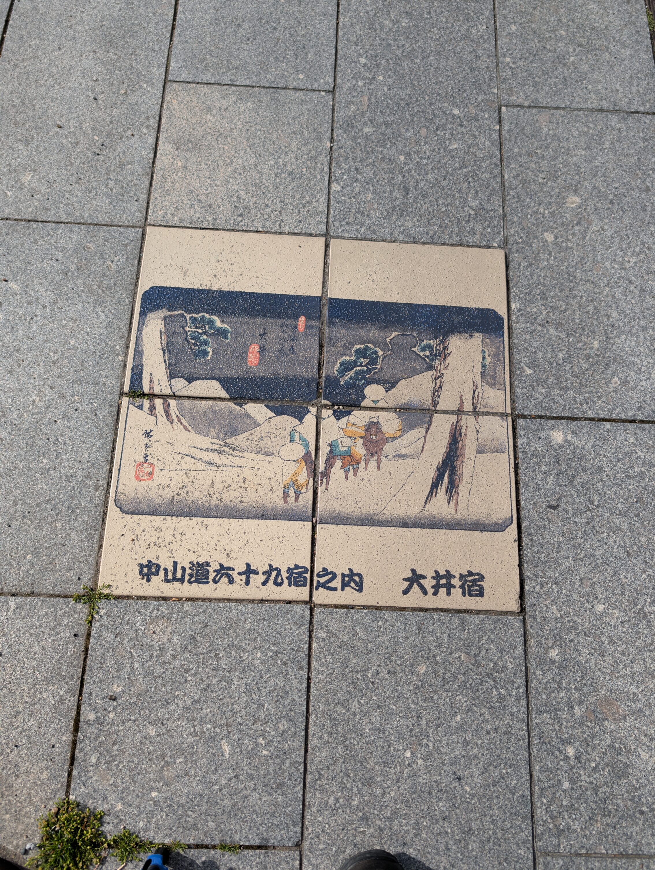 Coloured tiles in the pavement showing a scene from the book 69 Stations of the Kisokaido.